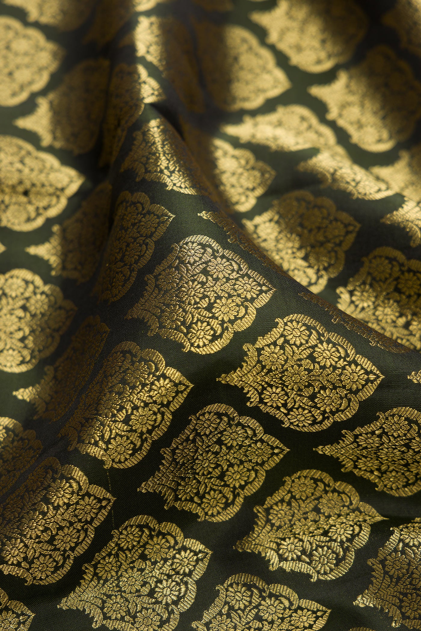 Close up of Bottle Green Kanchipuram Silk Saree with Zari Brocade on the body and Zari Border.  displaying folds