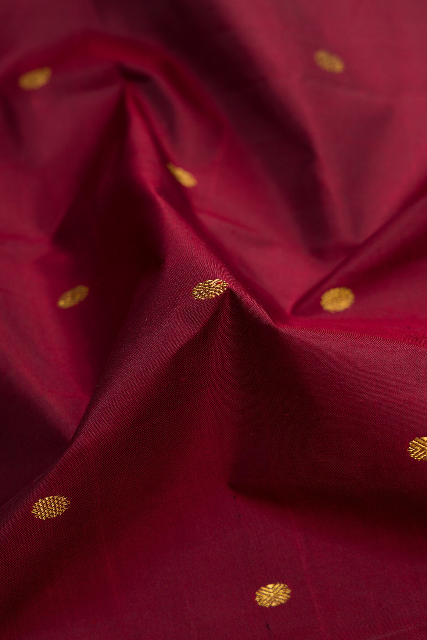 Close up of Maroon Dual Tone Kanjivaram Silk Saree with Zari Butta on the body and Zari Border.  displaying folds