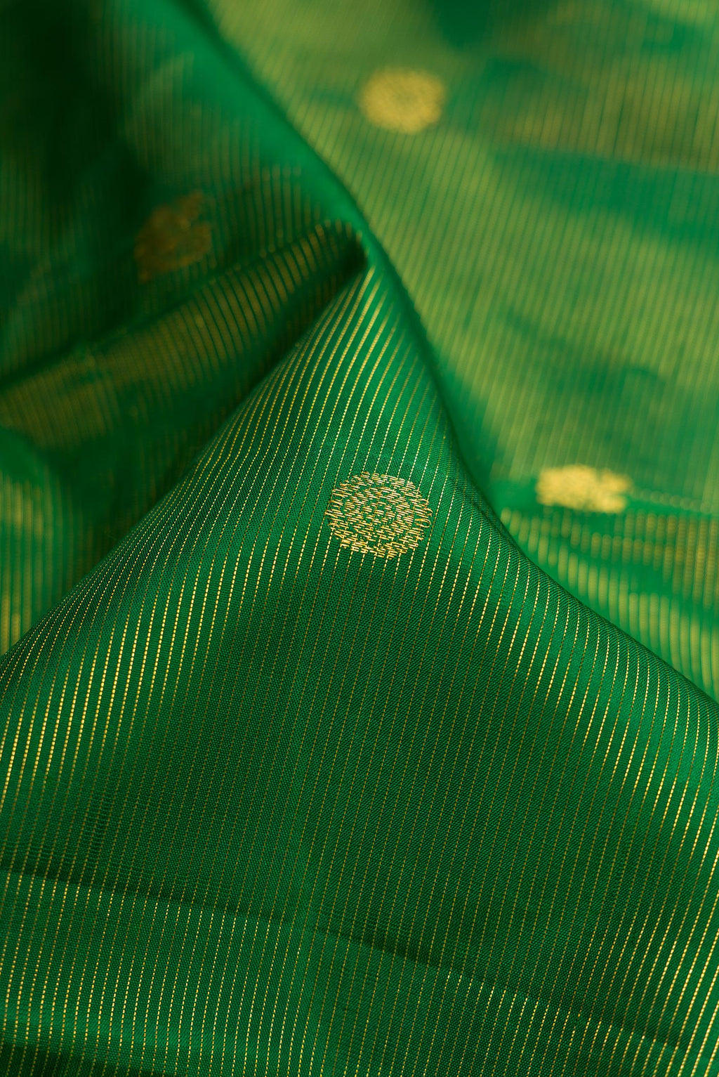 Close up of Pure Silk Pure Zari Green Dual Tone Kanjivaram Saree with Stripes on the body and Zari Border.  displaying folds