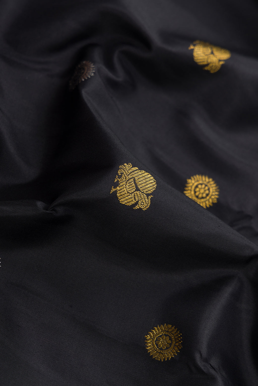 Close up of Black Dual Tone Kanchipuram Silk Saree with Zari Butta on the body and Temple Border.  displaying folds
