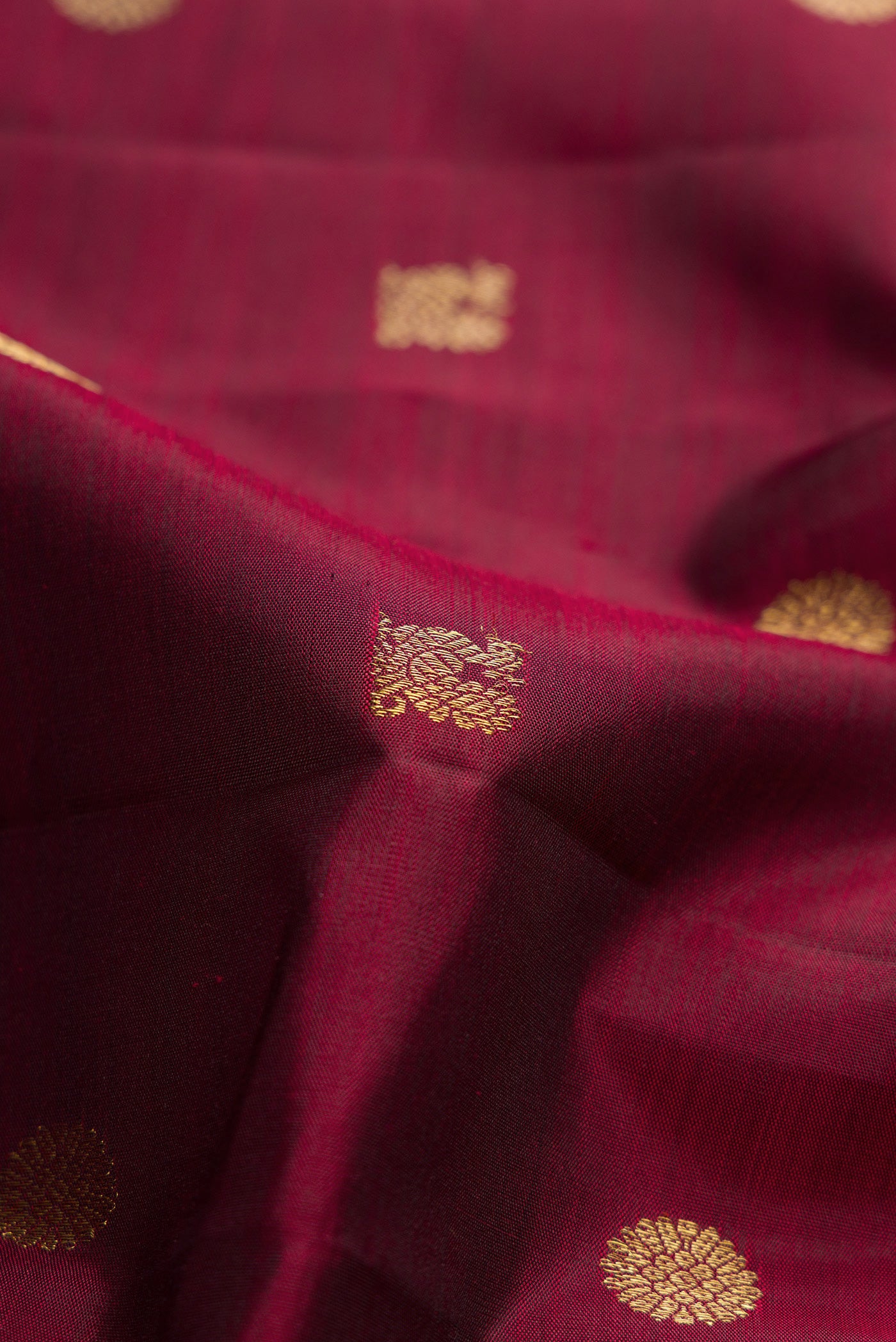 Close up of Pure Silk Pure Zari Maroon Dual Tone Kanchipuram Saree with Zari Butta on the body and Zari Border.  displaying folds