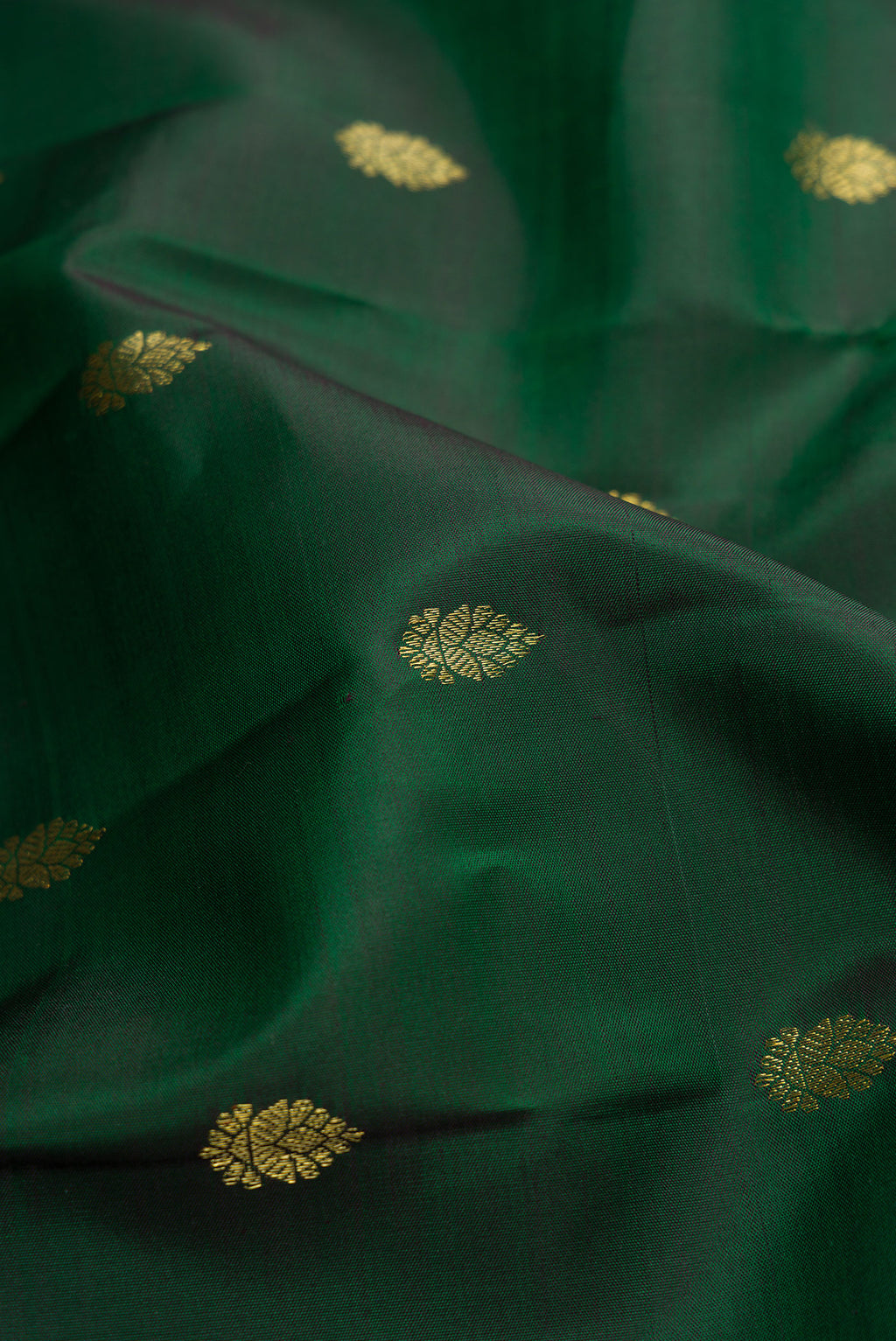 Close up of Green Dual Tone Kanchipuram Silk Saree with Zari Butta on the body and Zari Border.  displaying folds