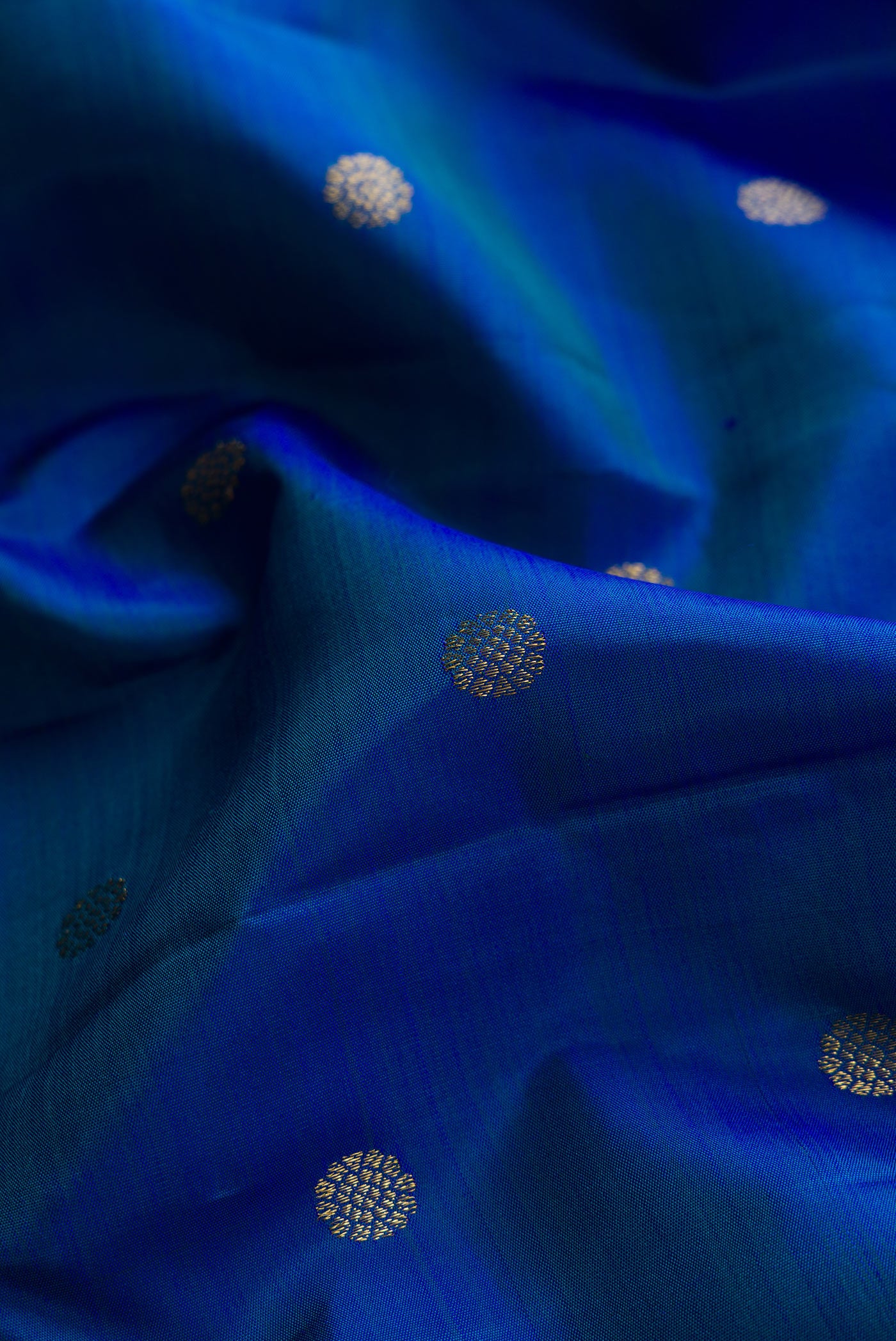 Close up of Peacock Blue Dual Tone Kanchipuram Silk Saree with Zari Butta on the body and Zari Border.  displaying folds