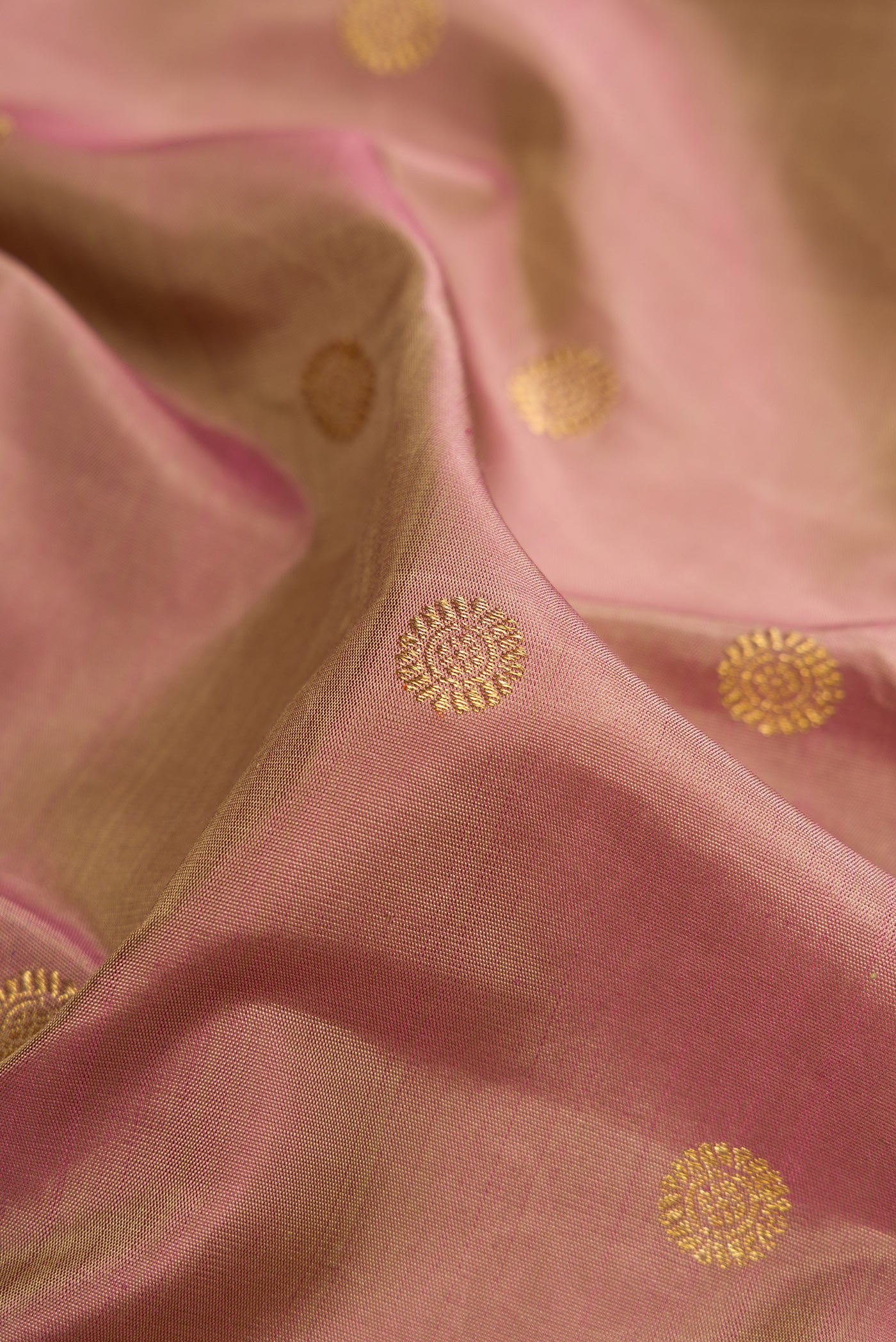 Close up of Pure Silk Pure Zari Rose Gold Kanjivaram Saree with Zari Butta on the body and Zari Border.  displaying folds