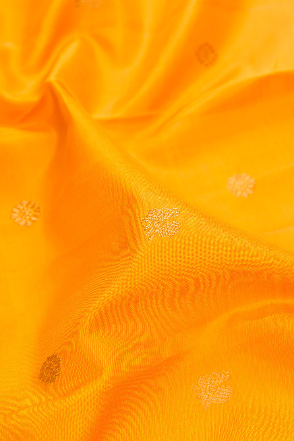 Close up of Pure Silk Pure Zari Mustard Kanjivaram Saree with Zari Butta on the body and Zari Border.  displaying folds