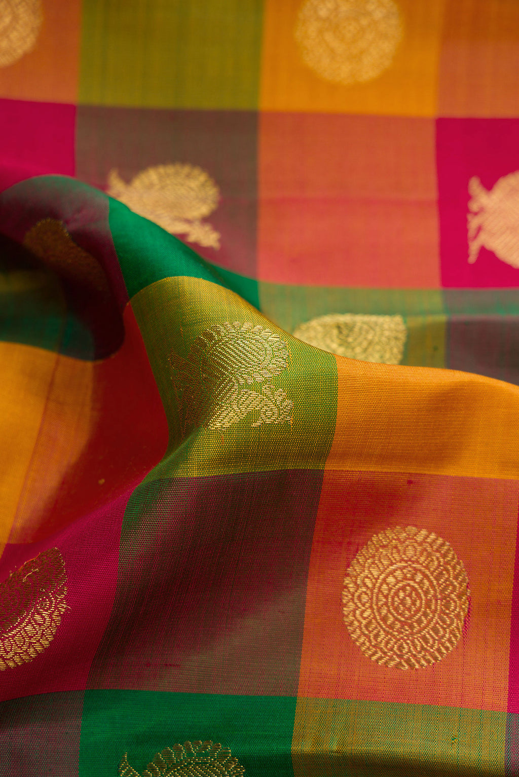 Close up of Green, Red and Mustard Color Kanchipuram Silk Saree with Checked design on the body and Without Border.  displaying folds