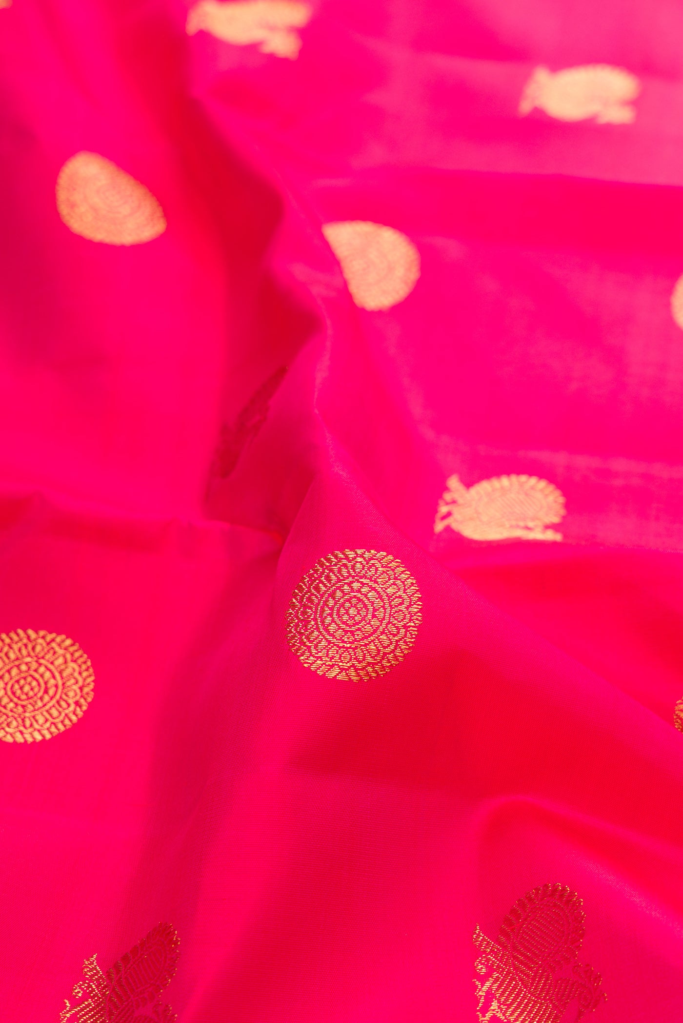 Close up of Pure Silk Pure Zari Pink Kanchipuram Saree with Zari Butta on the body and Zari Border.  displaying folds
