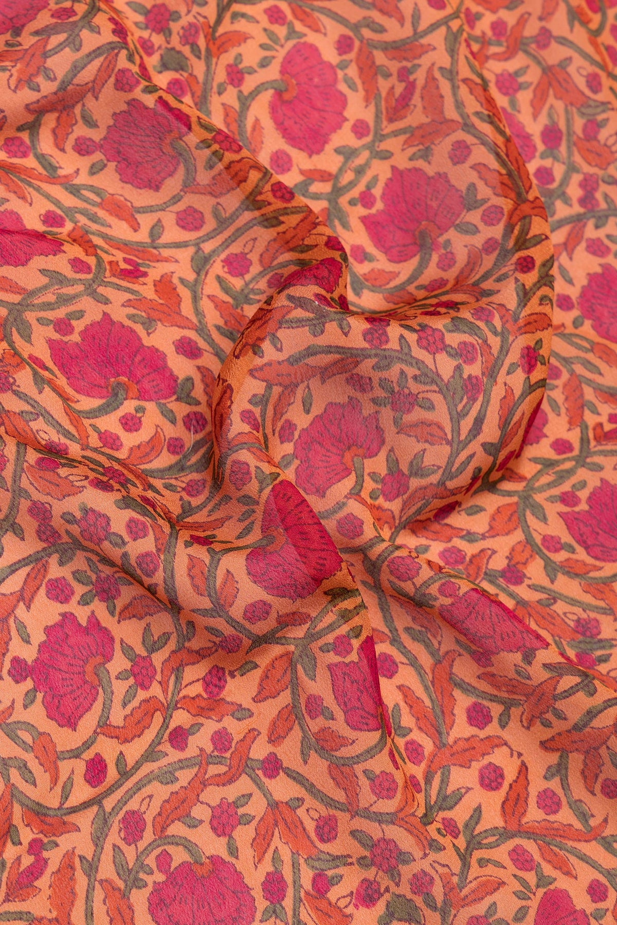 Close up of Orange Crepe Saree with Printed design on the body and Zari Border.  displaying folds