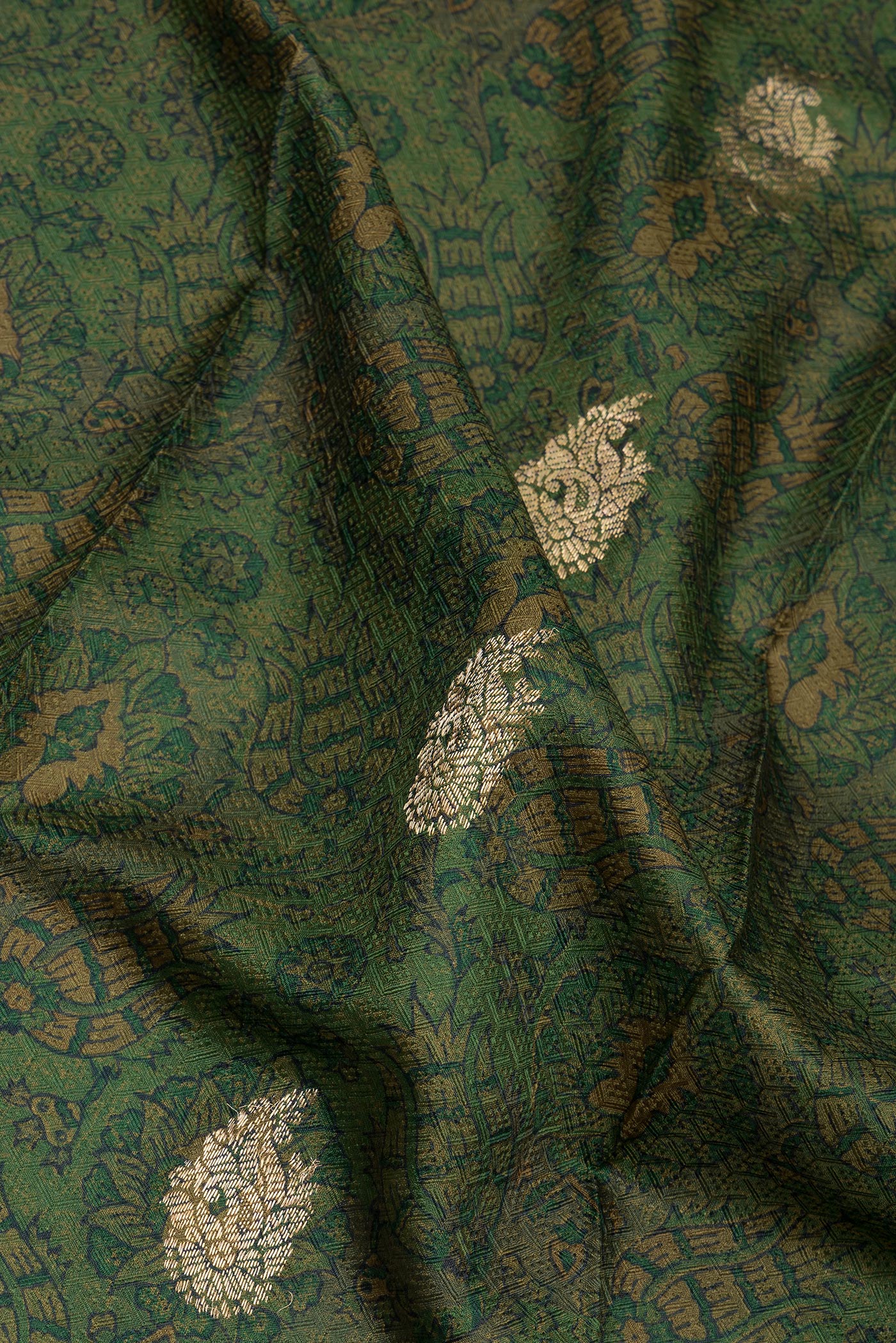 Close up of Mehandi Green Kanchipuram Silk Saree with Printed design on the body and Zari Border.  displaying folds