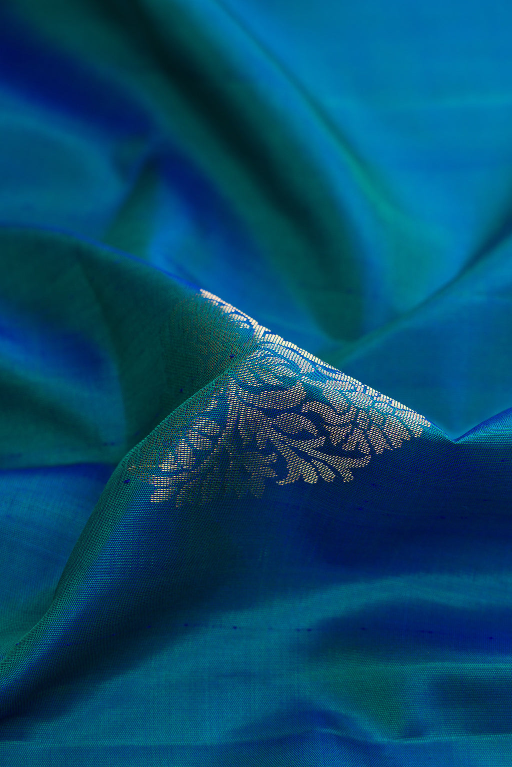 Close up of Peacock Blue Dual Tone Soft Silk Saree with Zari Butta on the body and Zari Border.  displaying folds