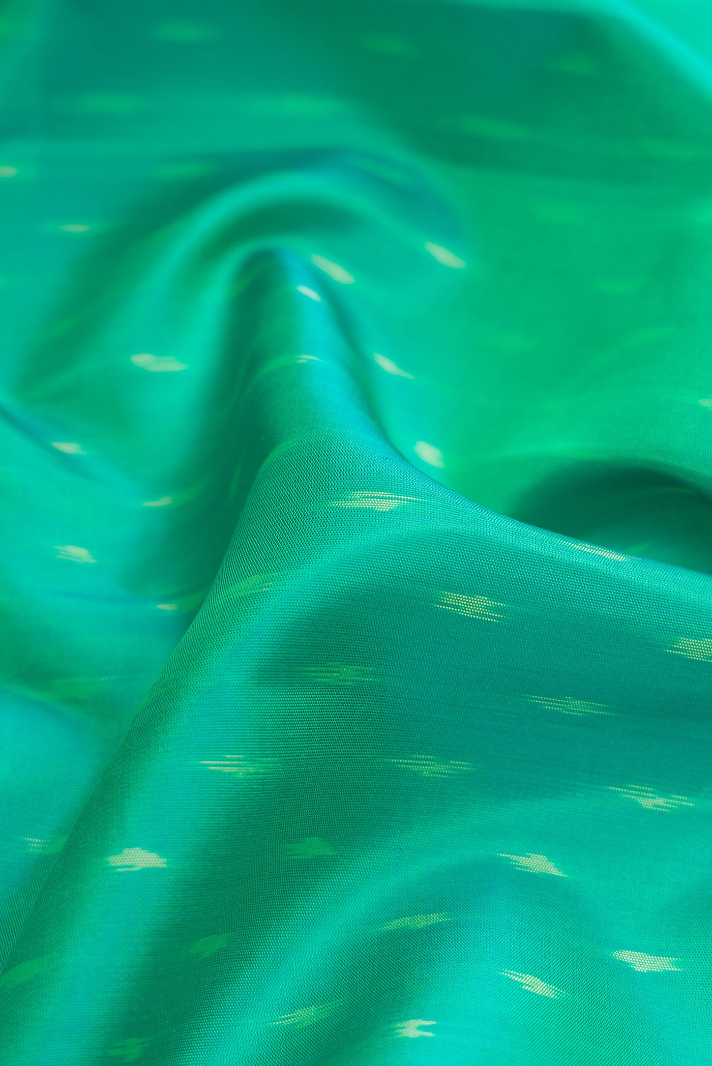Close up of Green Dual Tone Soft Silk Saree with Ikat Print on the body and Ikat Border.  displaying folds