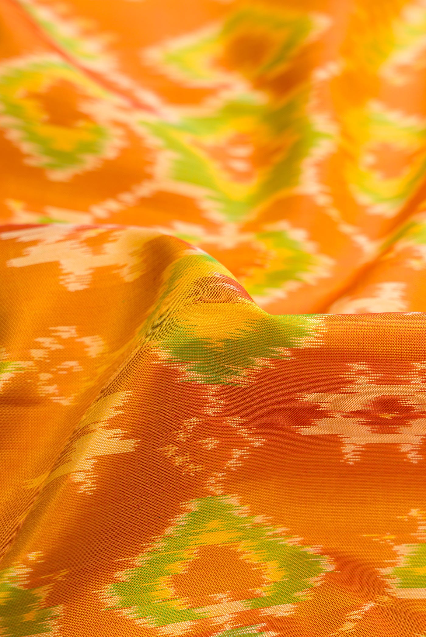 Close up of Mustard Dual Tone Soft Silk Saree with Ikat Print on the body and Ikat Border.  displaying folds