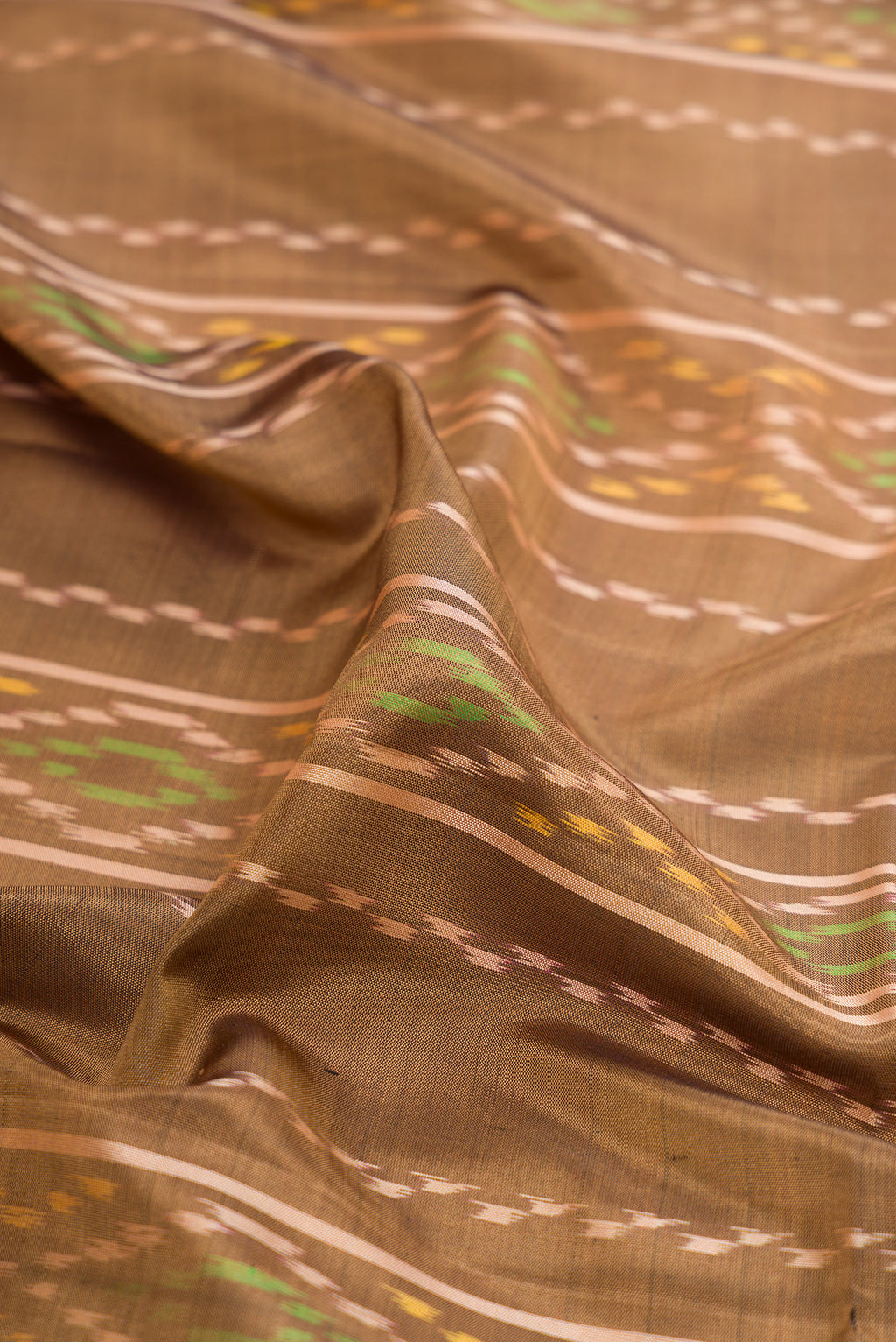 Close up of Dark Beige Soft Silk Saree with Ikat design on the body and Zari Border.  displaying folds