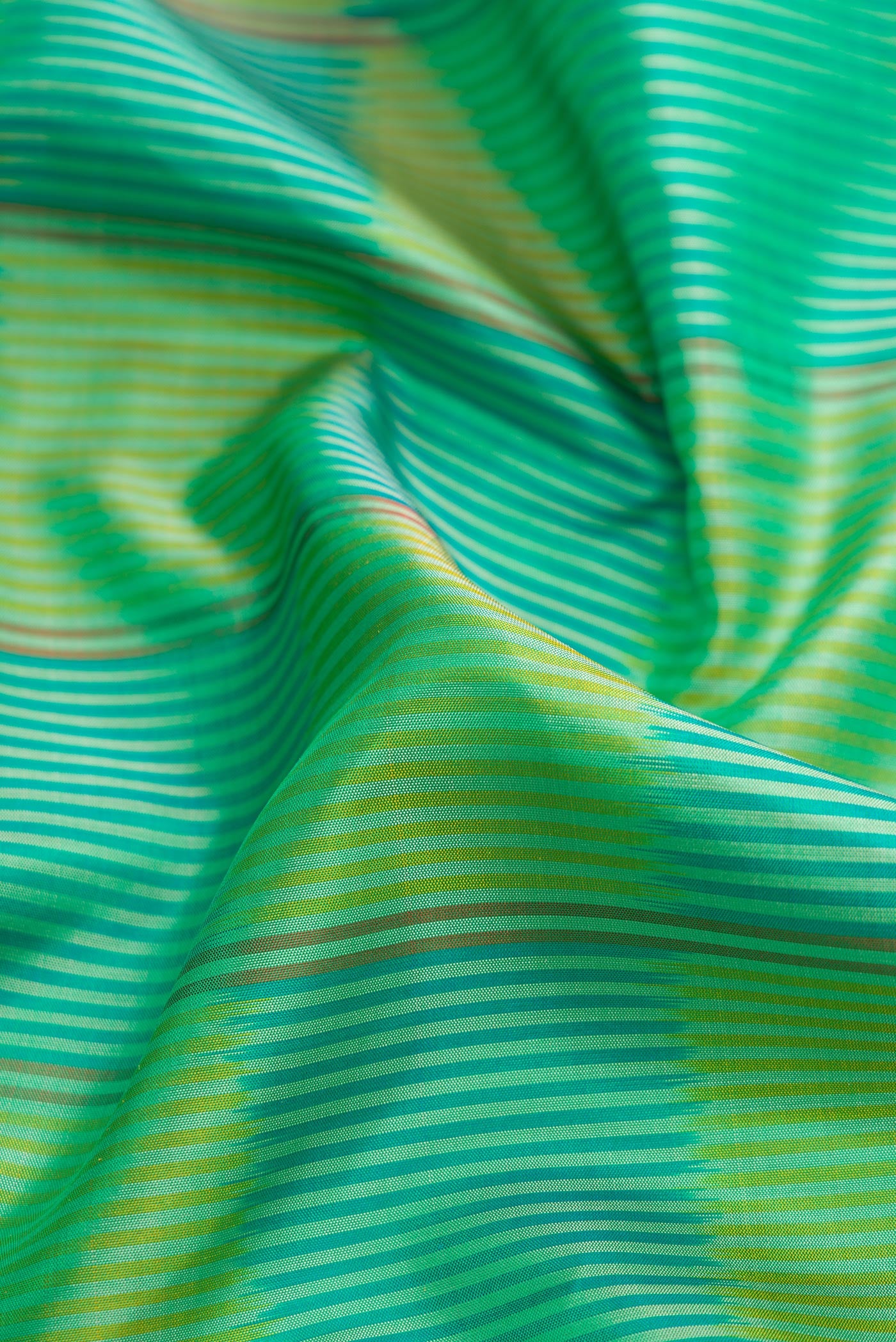Close up of Green Dual Tone Soft Silk Saree with Ikat Print on the body and Zari Border.  displaying folds
