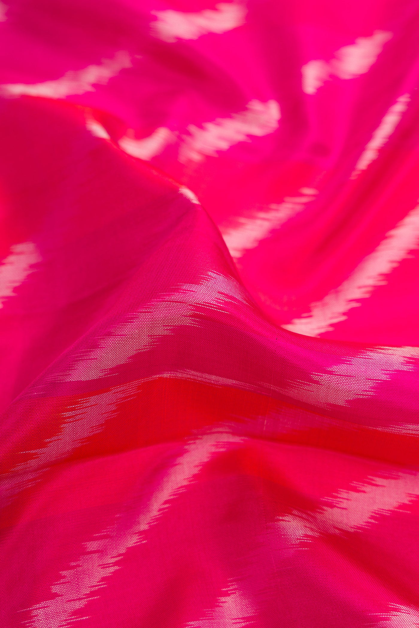 Close up of Pink Dual Tone Soft Silk Saree with Ikat Print on the body and Zari Border.  displaying folds