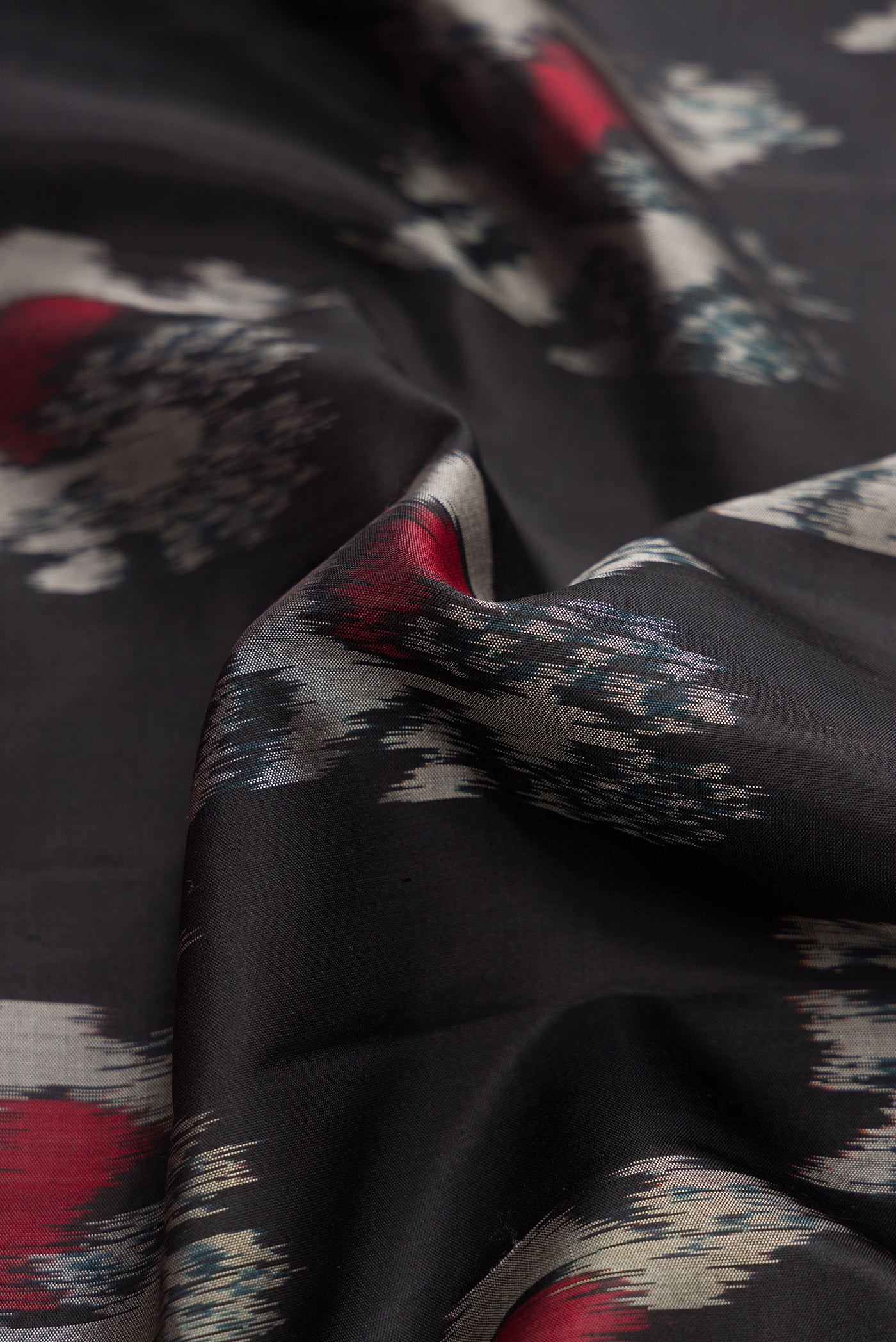Close up of Black Dual Tone Soft Silk Saree with Ikat Print on the body and Zari Border.  displaying folds