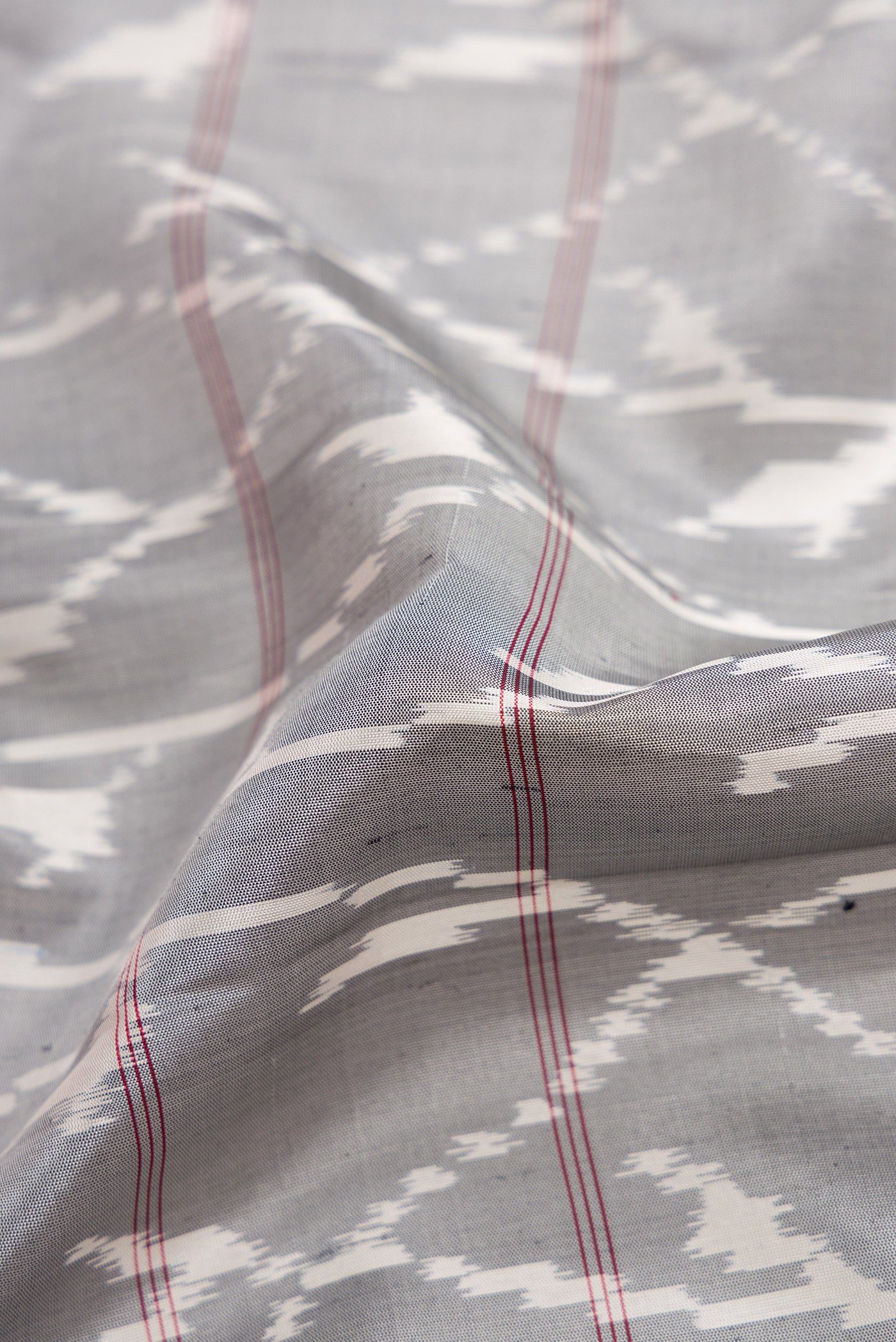 Close up of Grey Dual Tone Soft Silk Saree with Ikat Print on the body and Zari Border.  displaying folds
