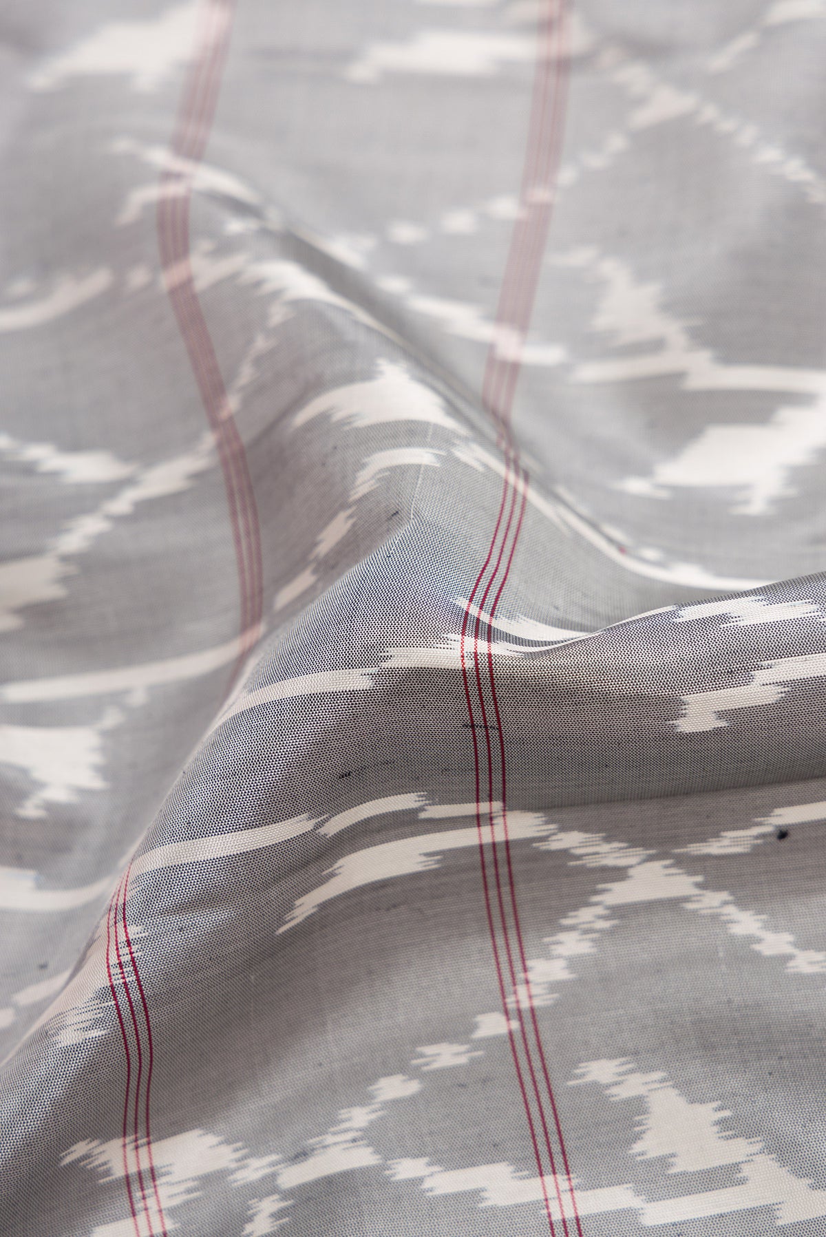 Close up of Grey Dual Tone Soft Silk Saree with Ikat Print on the body and Zari Border.  displaying folds