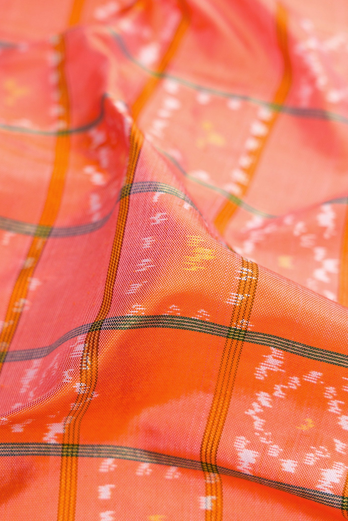 Close up of Peach Dual Tone Double Ikat Saree with Ikat Print on the body and Ikat Border.  displaying folds
