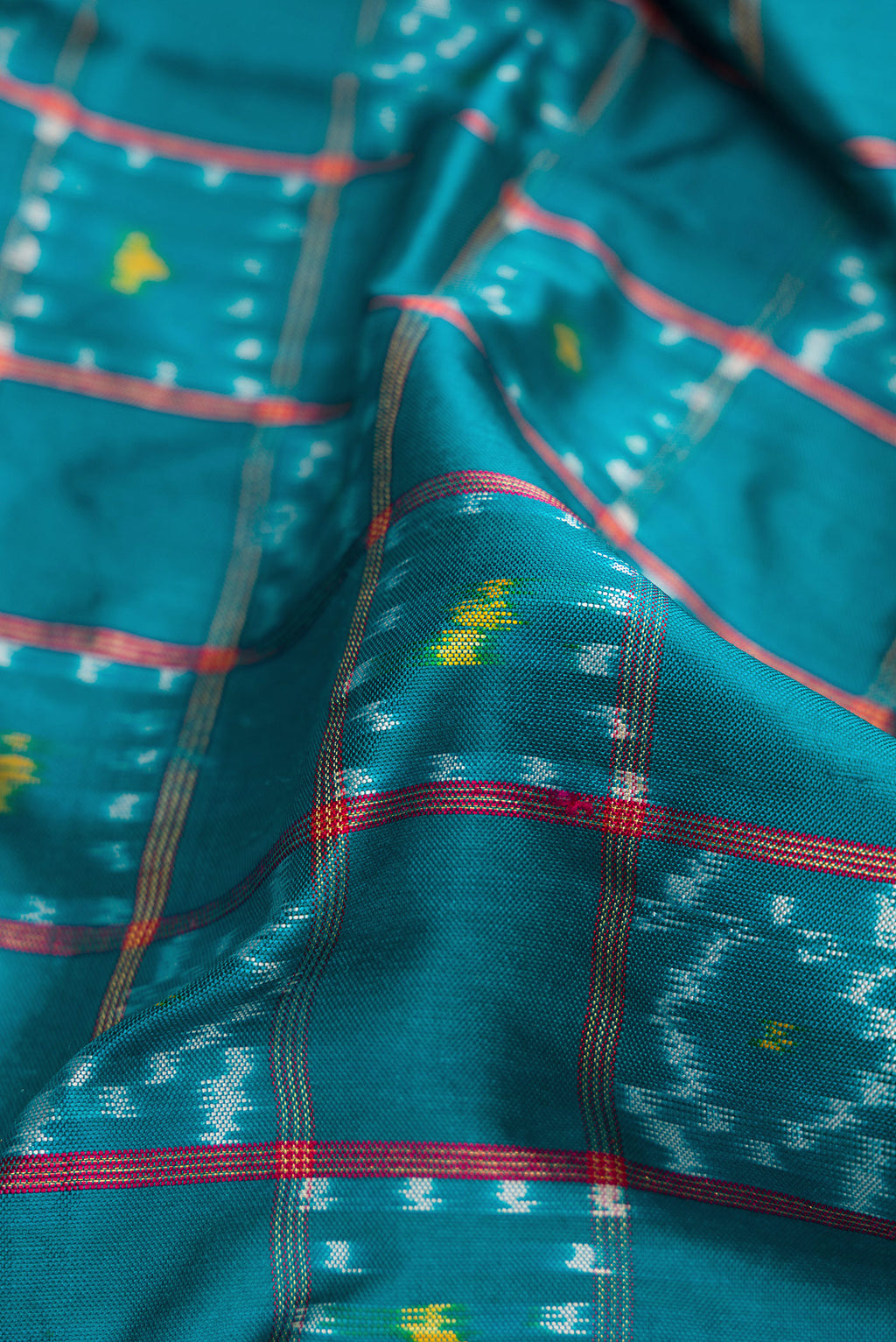 Close up of Peacock Blue Dual Tone Double Ikat Saree with Ikat Print on the body and Ikat Border.  displaying folds