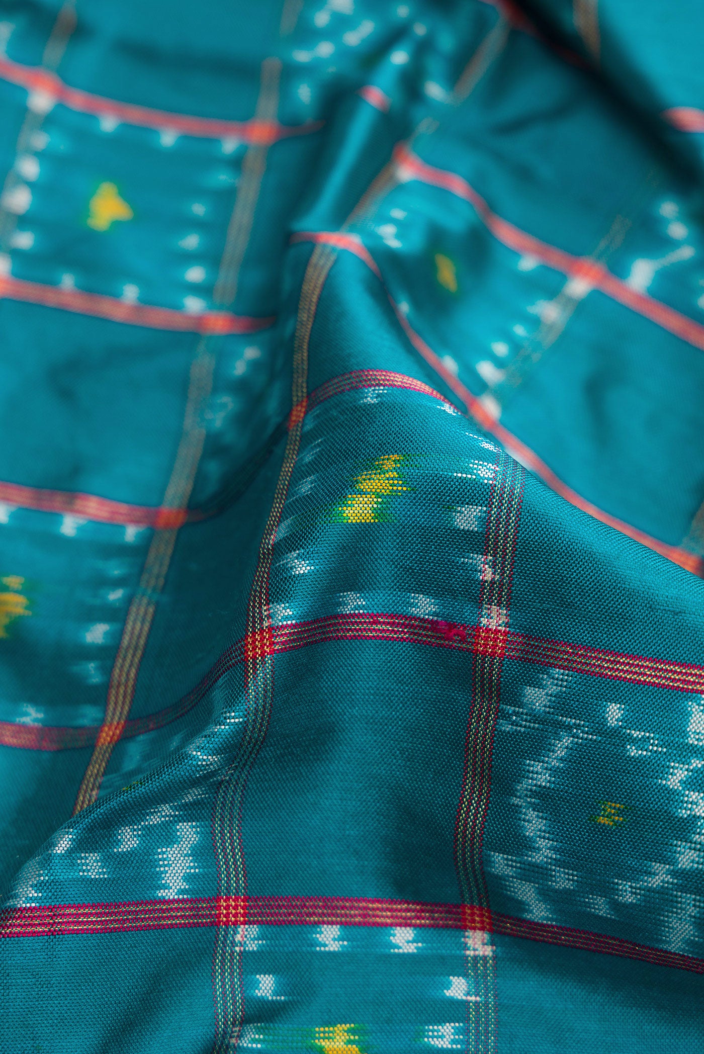 Close up of Peacock Blue Dual Tone Double Ikat Saree with Ikat Print on the body and Ikat Border.  displaying folds