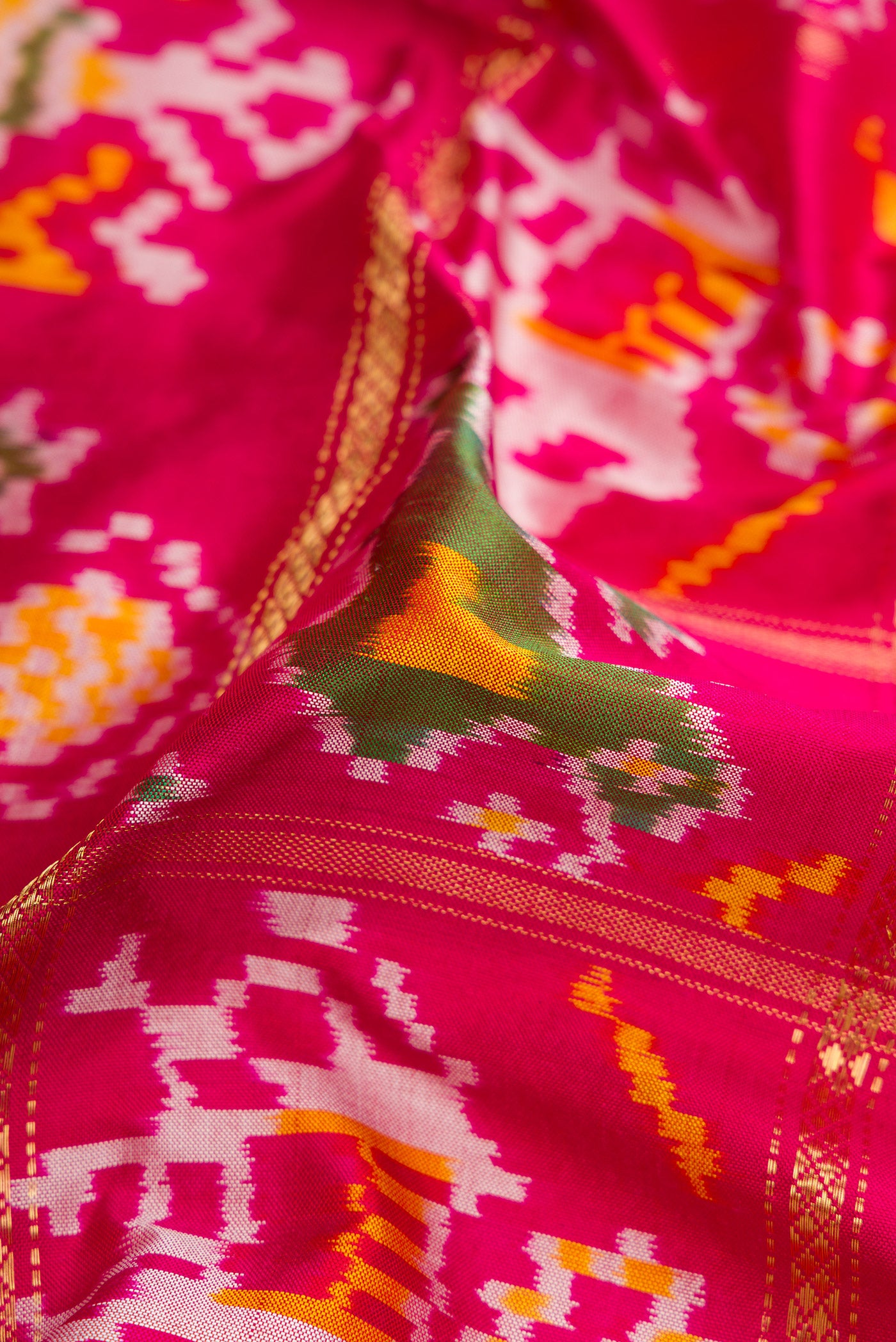 Close up of Pink Dual Tone Double Ikat Saree with Ikat Print on the body and Zari Border.  displaying folds
