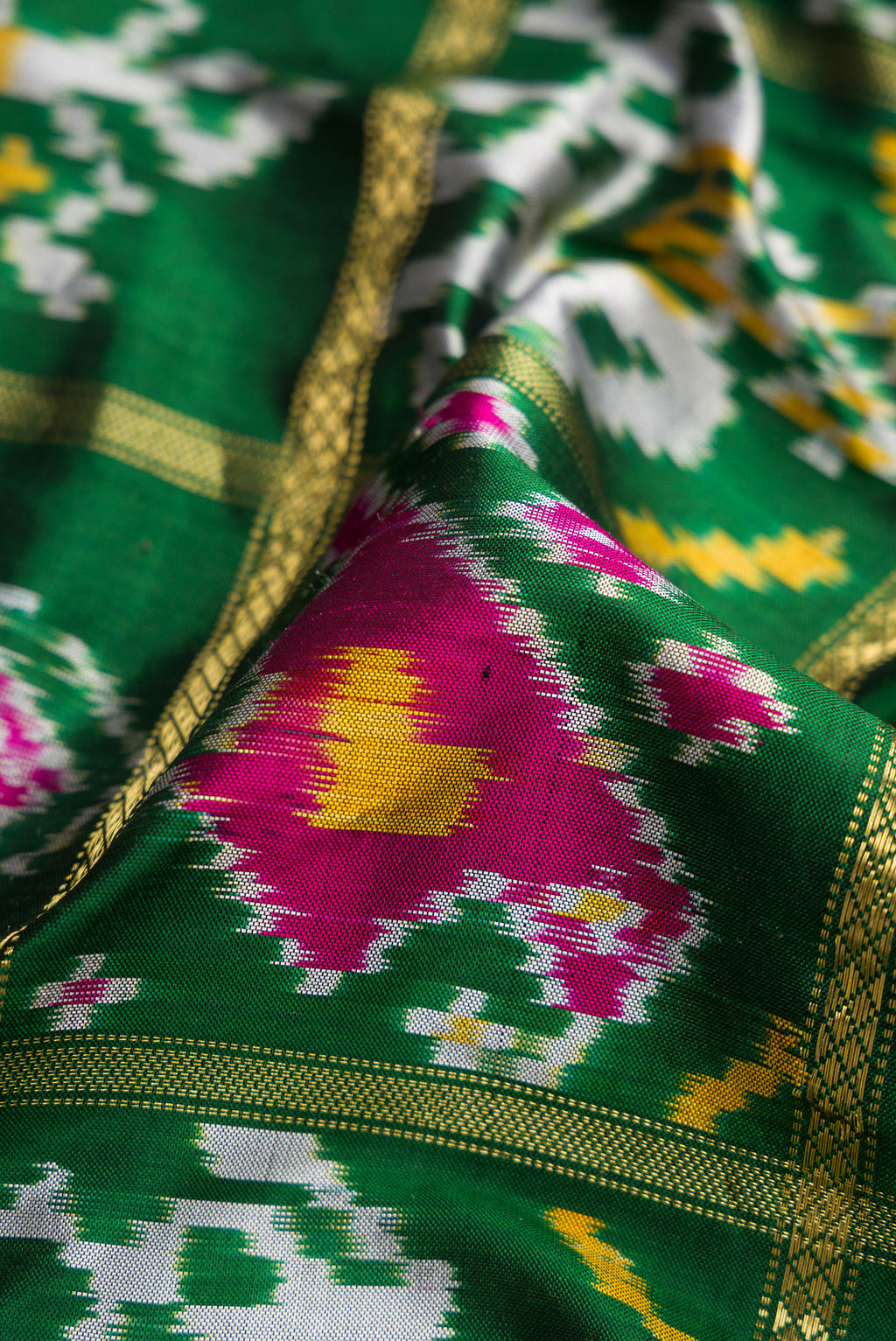Close up of Bottle Green Dual Tone Double Ikat Saree with Ikat Print on the body and Zari Border.  displaying folds