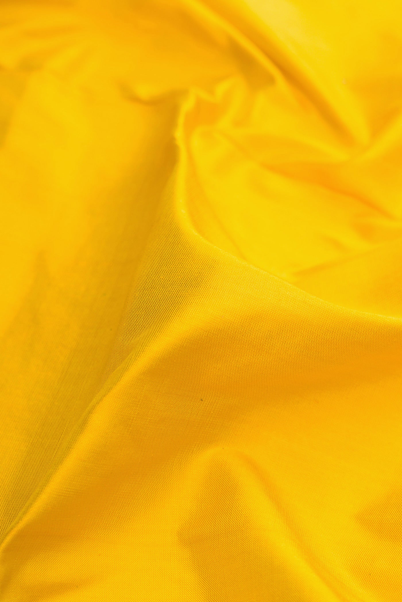 Close up of Yellow Dual Tone Double Ikat Saree with Plain Body and Zari Border.  displaying folds