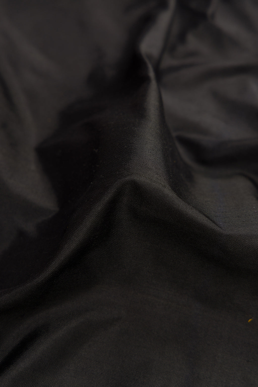 Close up of Black Dual Tone Double Ikat Saree with Plain Body and Zari Border.  displaying folds
