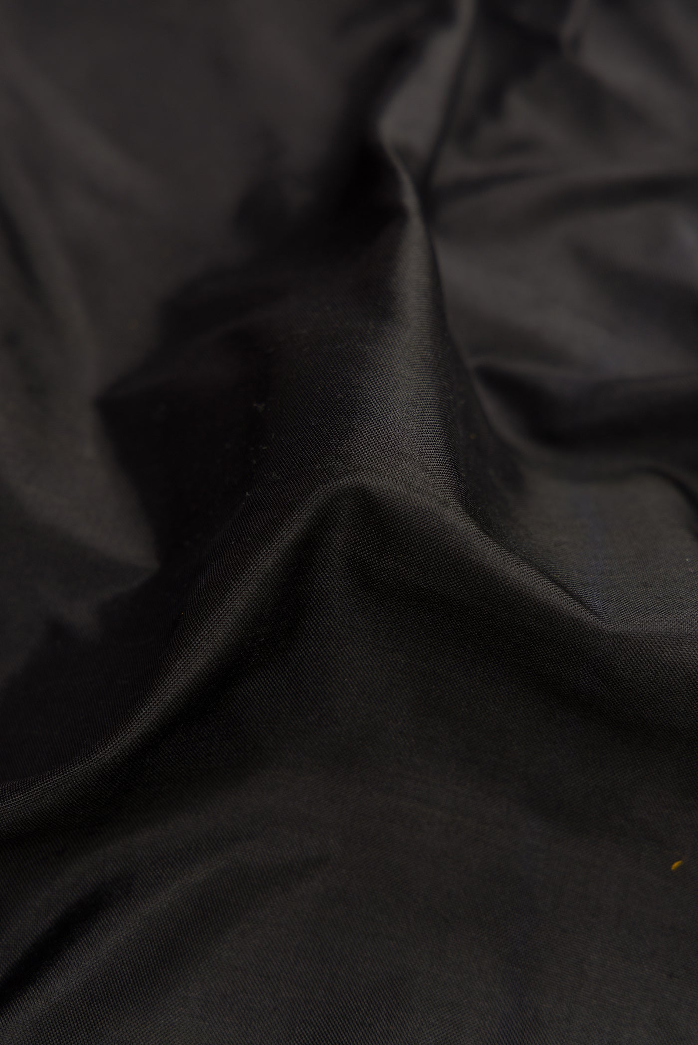 Close up of Black Dual Tone Double Ikat Saree with Plain Body and Zari Border.  displaying folds