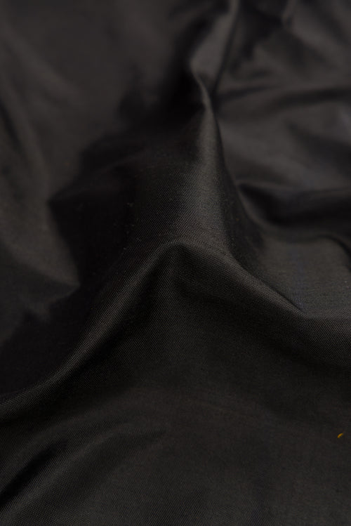 Close up of Black Dual Tone Double Ikat Saree with Plain Body and Zari Border.  displaying folds