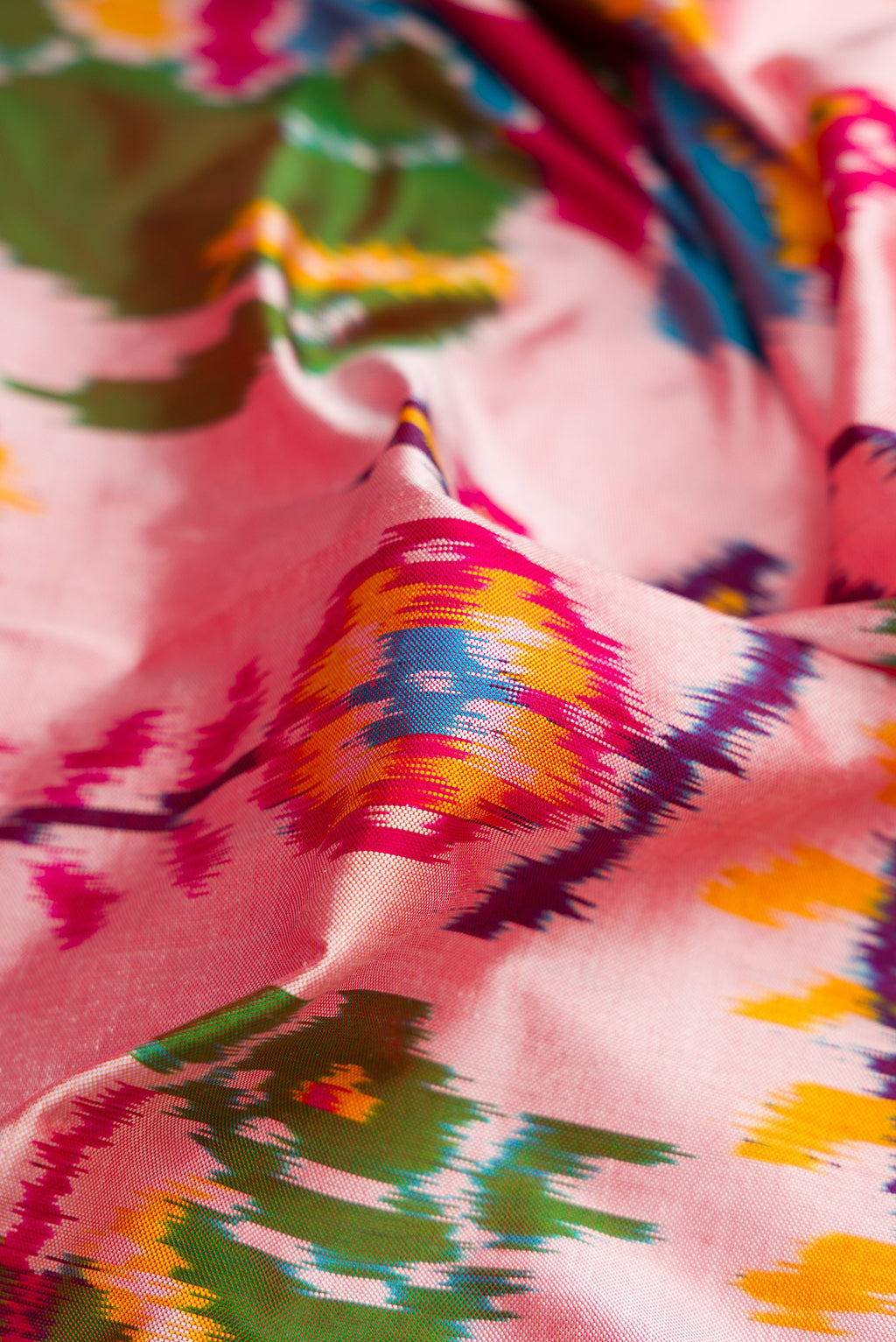 Close up of Pink Dual Tone Double Ikat Saree with Ikat Print on the body and Thread Border.  displaying folds