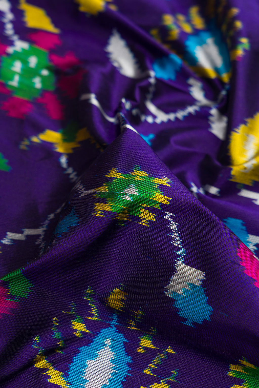 Close up of Violet Dual Tone Double Ikat Saree with Ikat Print on the body and Thread Border.  displaying folds