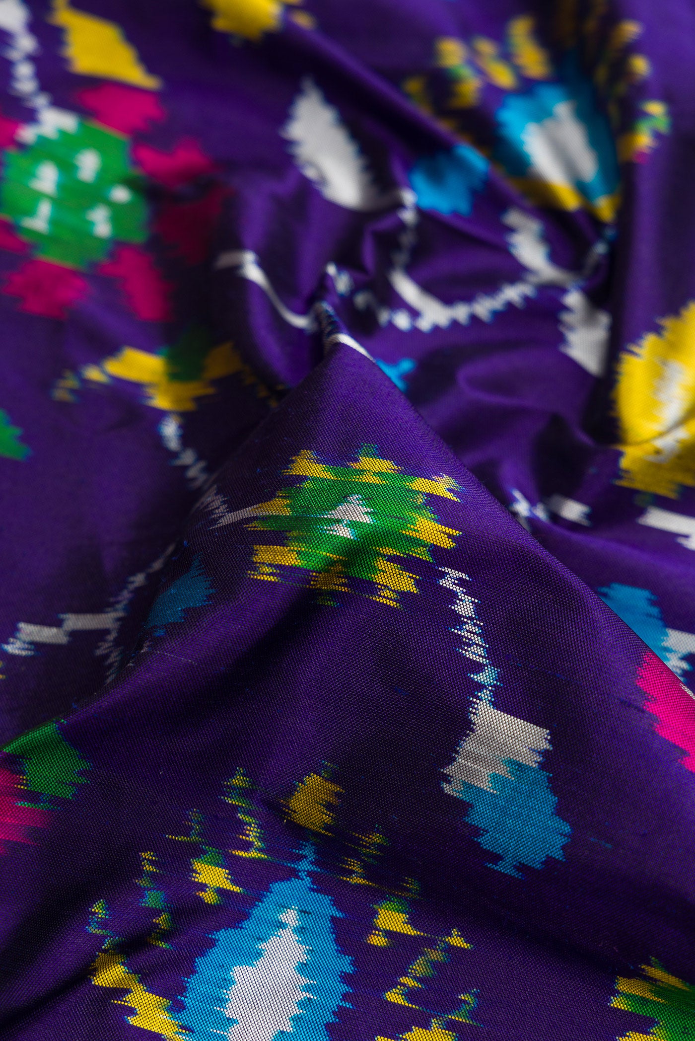 Close up of Violet Dual Tone Double Ikat Saree with Ikat Print on the body and Thread Border.  displaying folds