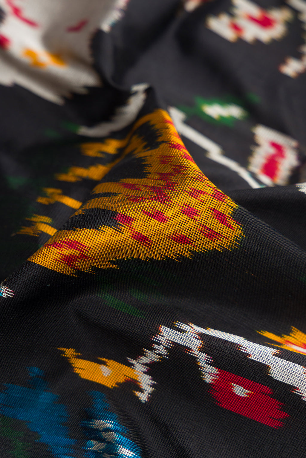 Close up of Black Dual Tone Double Ikat Saree with Ikat Print on the body and Thread Border.  displaying folds