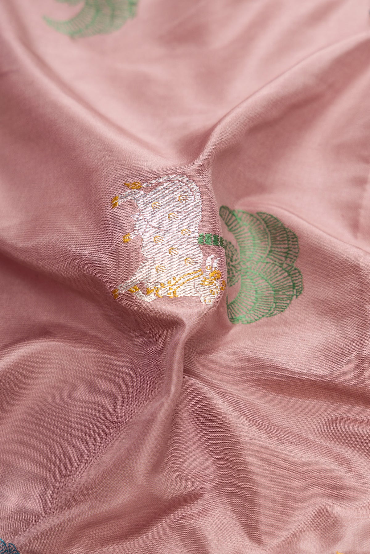 Close up of Rose Gold Dual Tone Banarasi Silk Saree with Zari And Thread Butta on the body and Fancy Border.  displaying folds