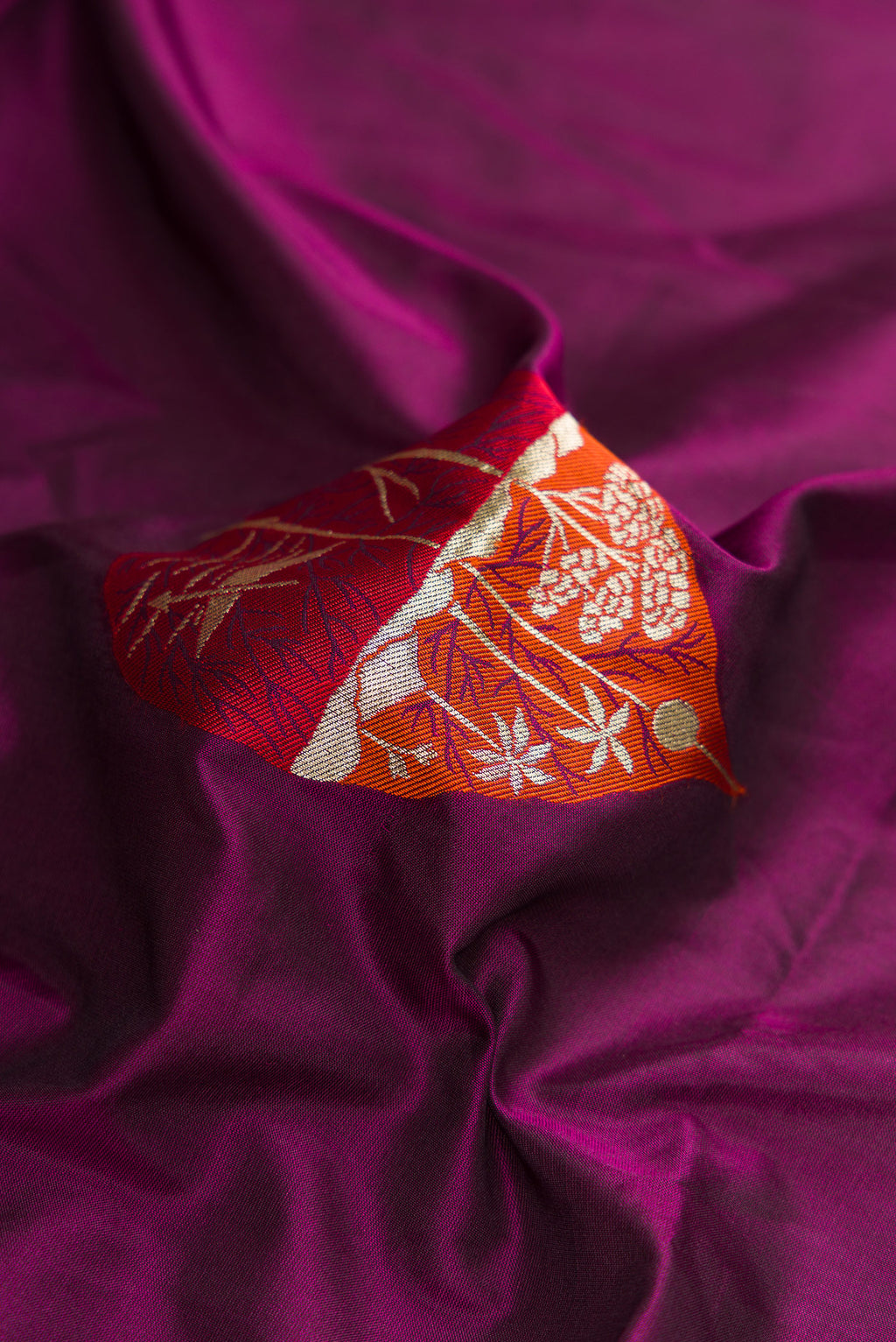 Close up of Burgundy Dual Tone Banarasi Silk Saree with Zari And Thread Butta on the body and Fancy Border.  displaying folds
