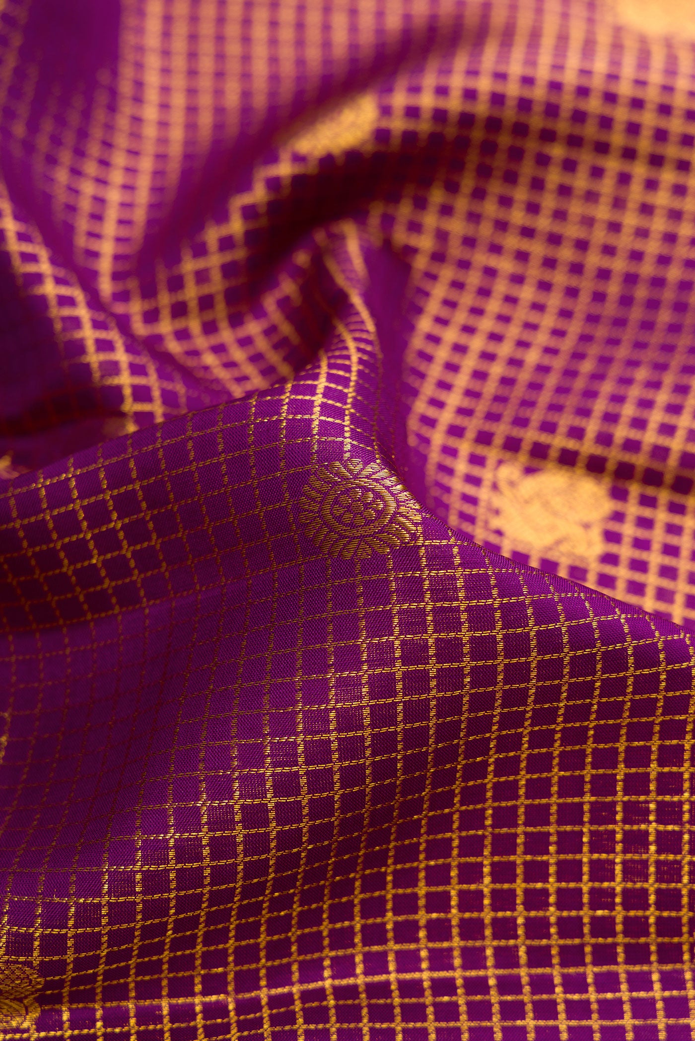 Close up of Violet Dual Tone Kanjivaram Silk Saree with Checked design on the body and Zari Border.  displaying folds