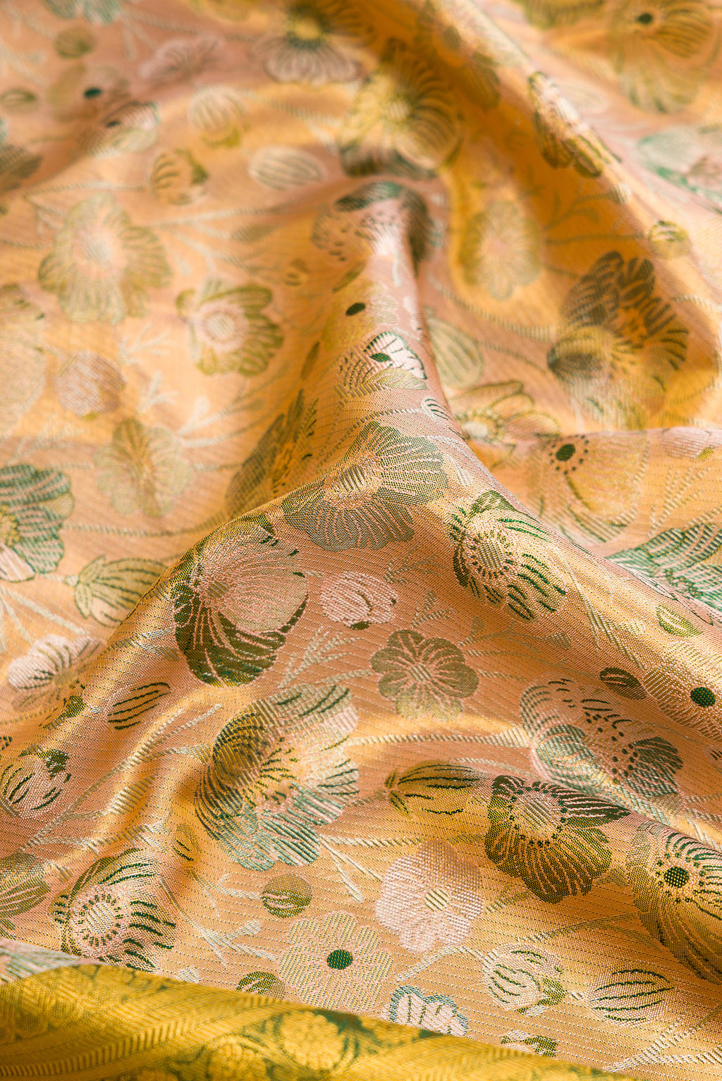 Close up of Peach Dual Tone Kanjivaram Tissue Silk Saree with Zari Brocade on the body and Zari Border.  displaying folds