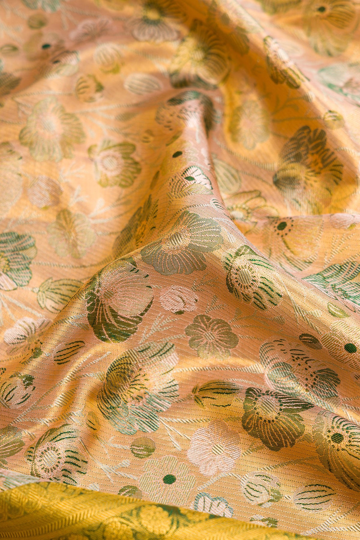 Close up of Peach Dual Tone Kanjivaram Tissue Silk Saree with Zari Brocade on the body and Zari Border.  displaying folds