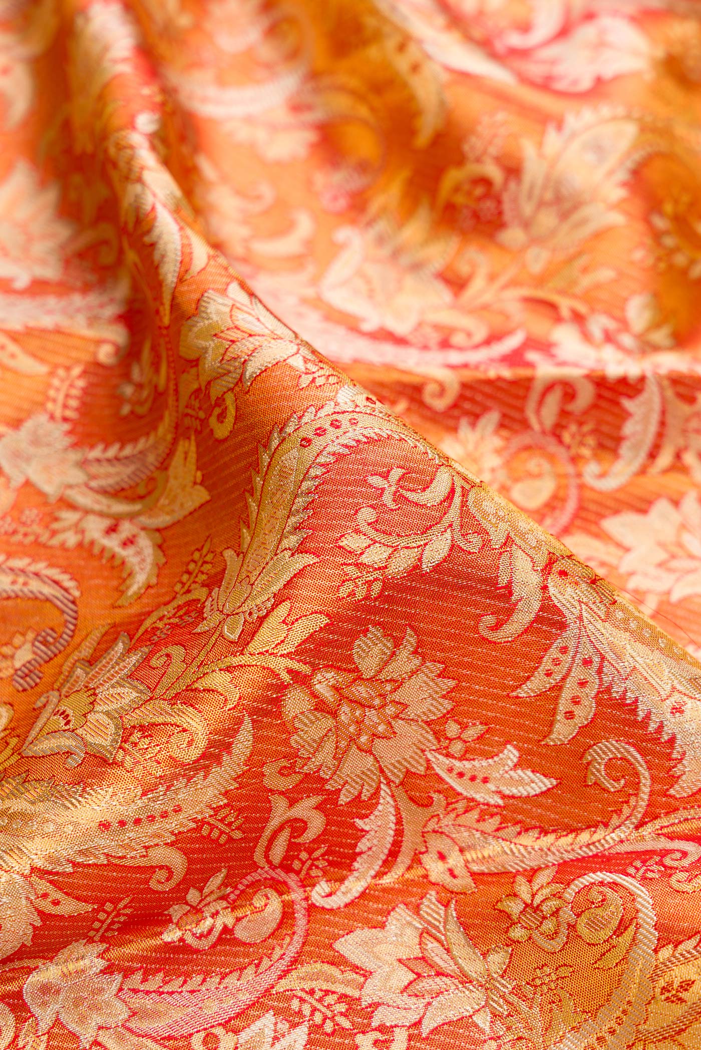 Close up of Orange Dual Tone Kanjivaram Tissue Silk Saree with Zari Brocade on the body and Fancy Border.  displaying folds