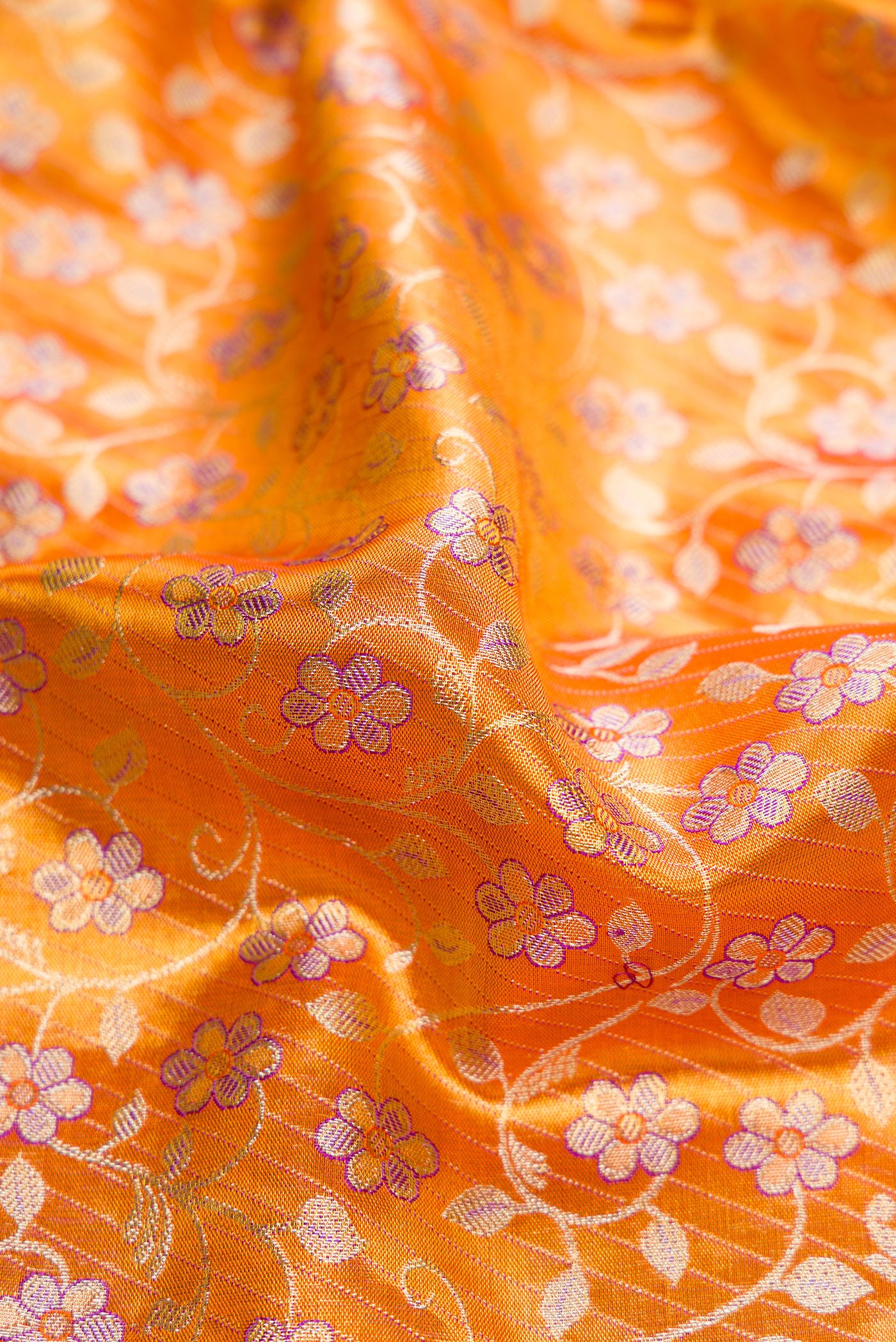 Close up of Golden Peach Dual Tone Kanjivaram Tissue Silk Saree with Zari Brocade on the body and Fancy Border.  displaying folds