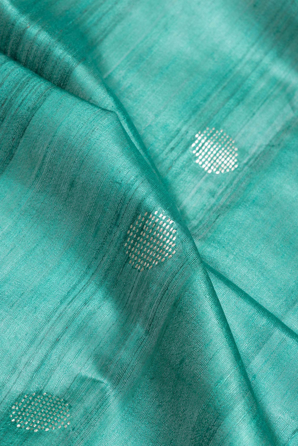 Close up of Green Dual Tone Tussar Silk Saree with Zari Butta on the body and Zari Border.  displaying folds