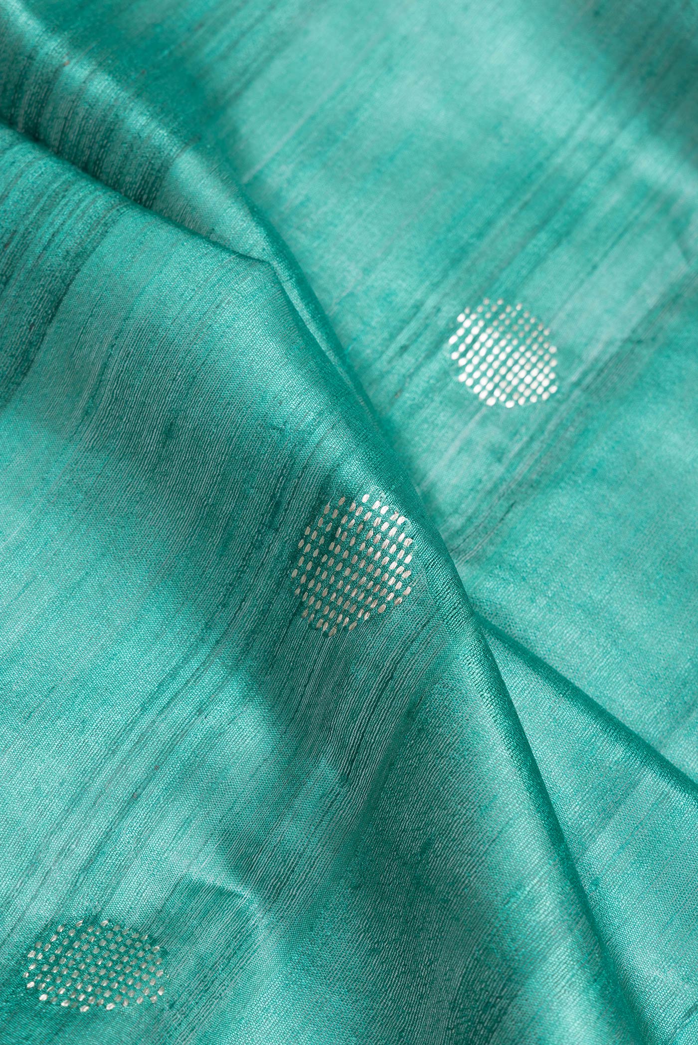 Close up of Green Dual Tone Tussar Silk Saree with Zari Butta on the body and Zari Border.  displaying folds