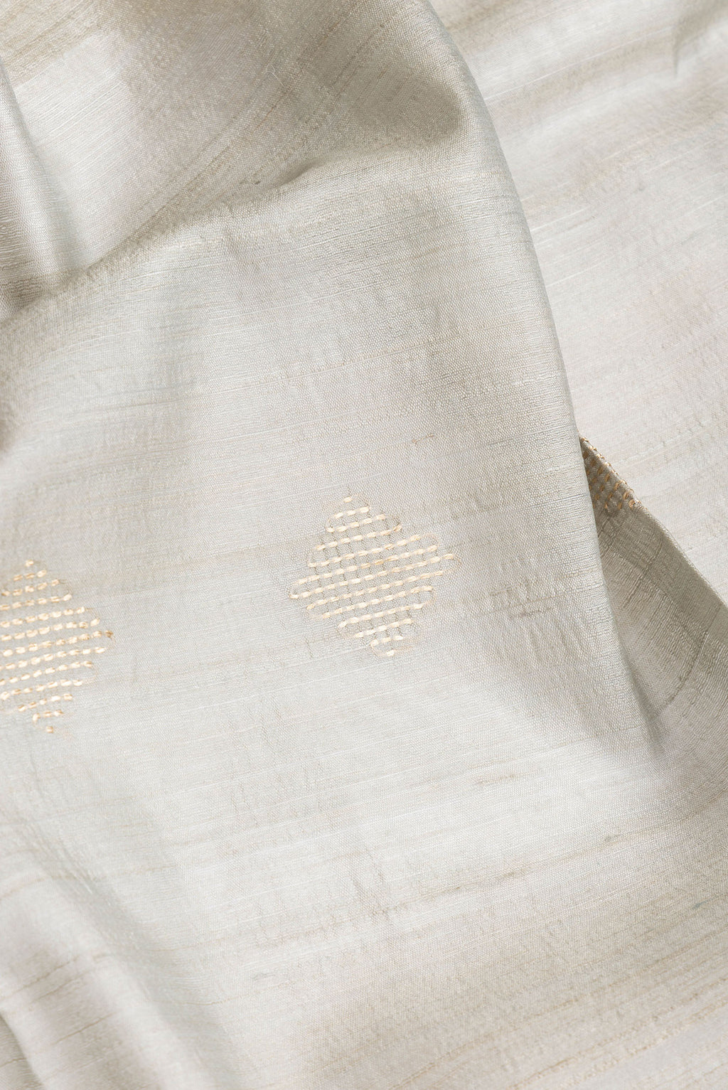 Close up of Blue Grey Dual Tone Tussar Silk Saree with Zari Butta on the body and Zari Border.  displaying folds
