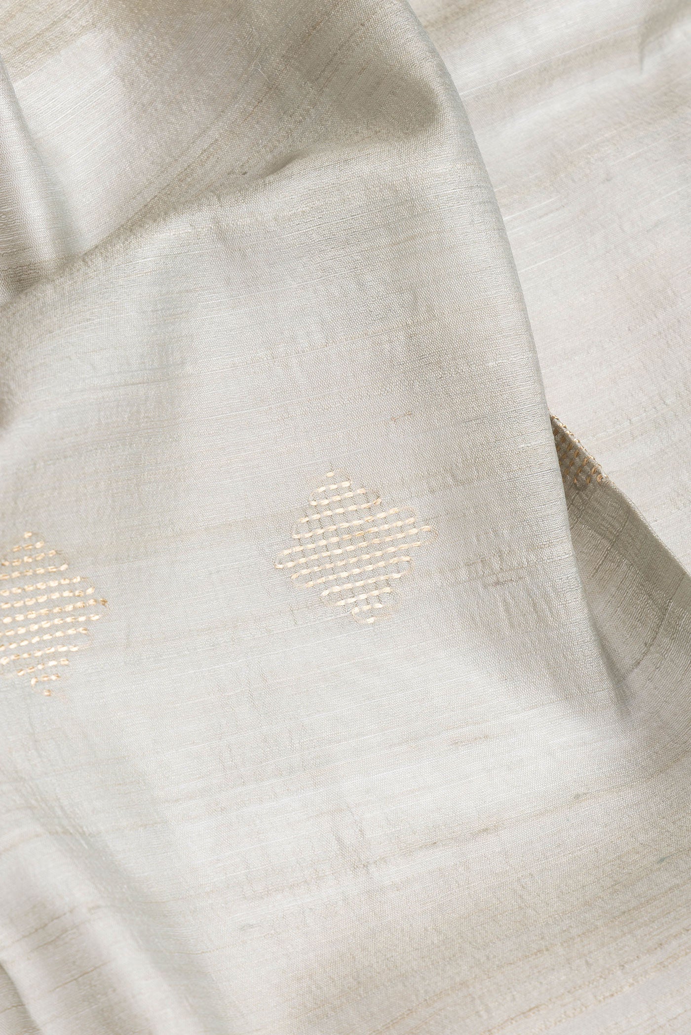 Close up of Blue Grey Dual Tone Tussar Silk Saree with Zari Butta on the body and Zari Border.  displaying folds