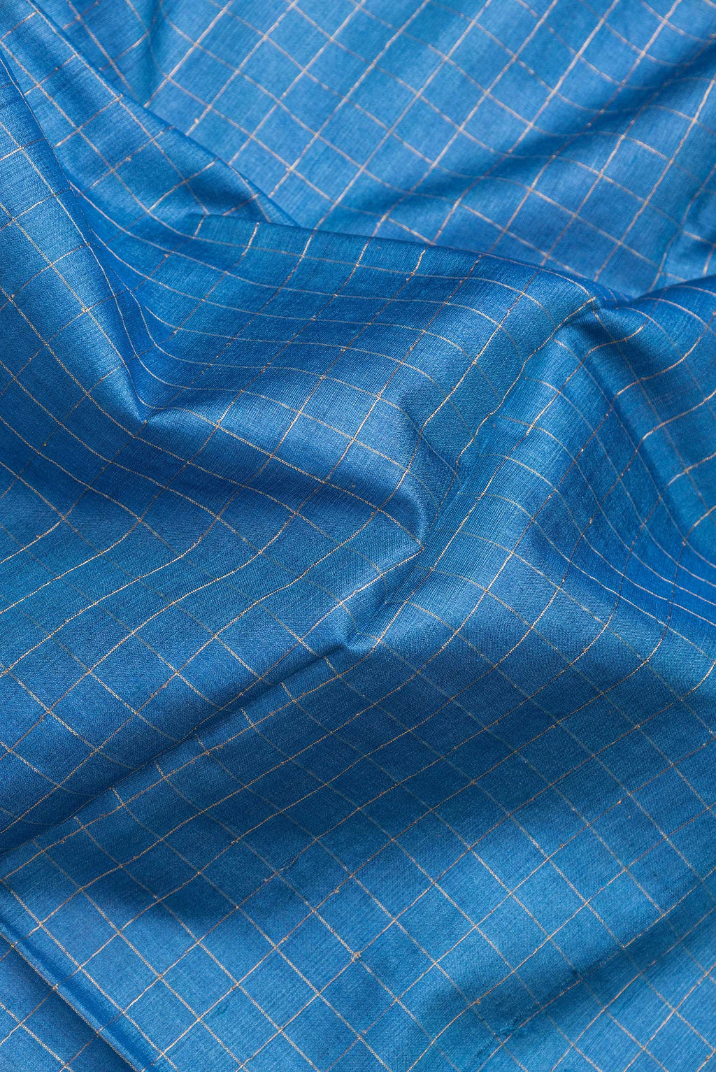 Close up of Royal Blue Dual Tone Tussar Silk Saree with Checked design on the body and Printed Border.  displaying folds