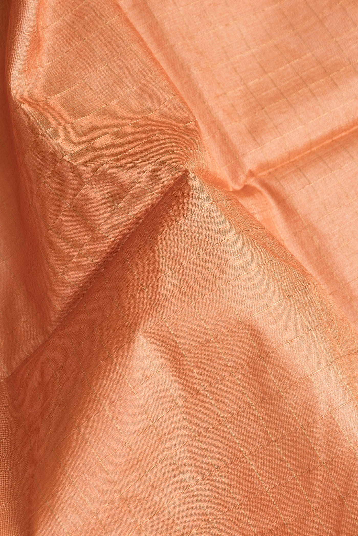 Close up of Golden Peach Dual Tone Tussar Silk Saree with Checked design on the body and Printed Border.  displaying folds