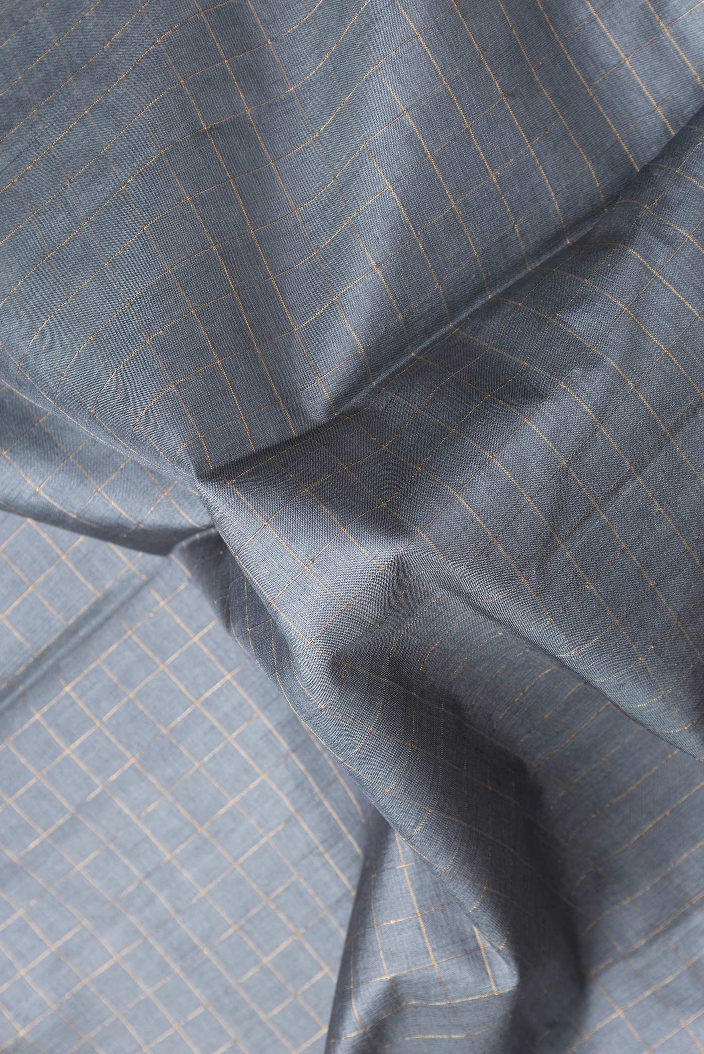 Close up of Grey Dual Tone Tussar Silk Saree with Checked design on the body and Printed Border.  displaying folds