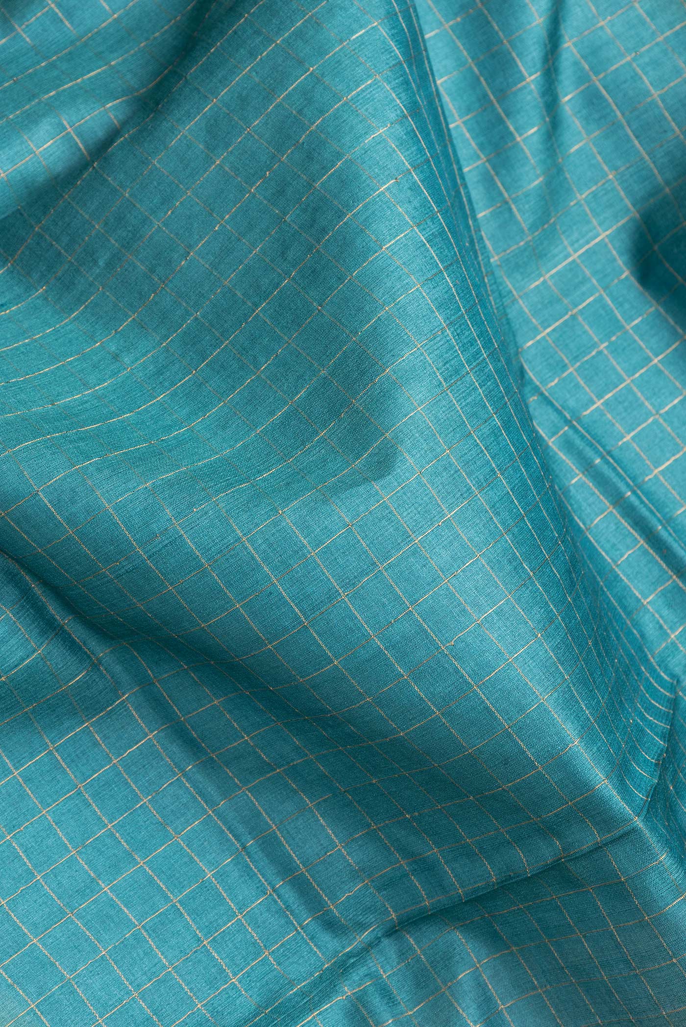 Close up of Sky Blue Dual Tone Tussar Silk Saree with Checked design on the body and Printed Border.  displaying folds